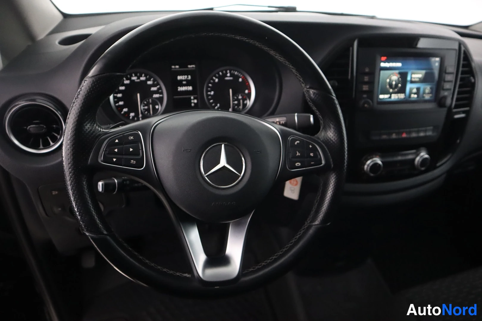 Yksityiskohta: Mercedes-ohjauspyörä lähikuvassa, monitoiminäppäimet ja mittaristo taustalla.