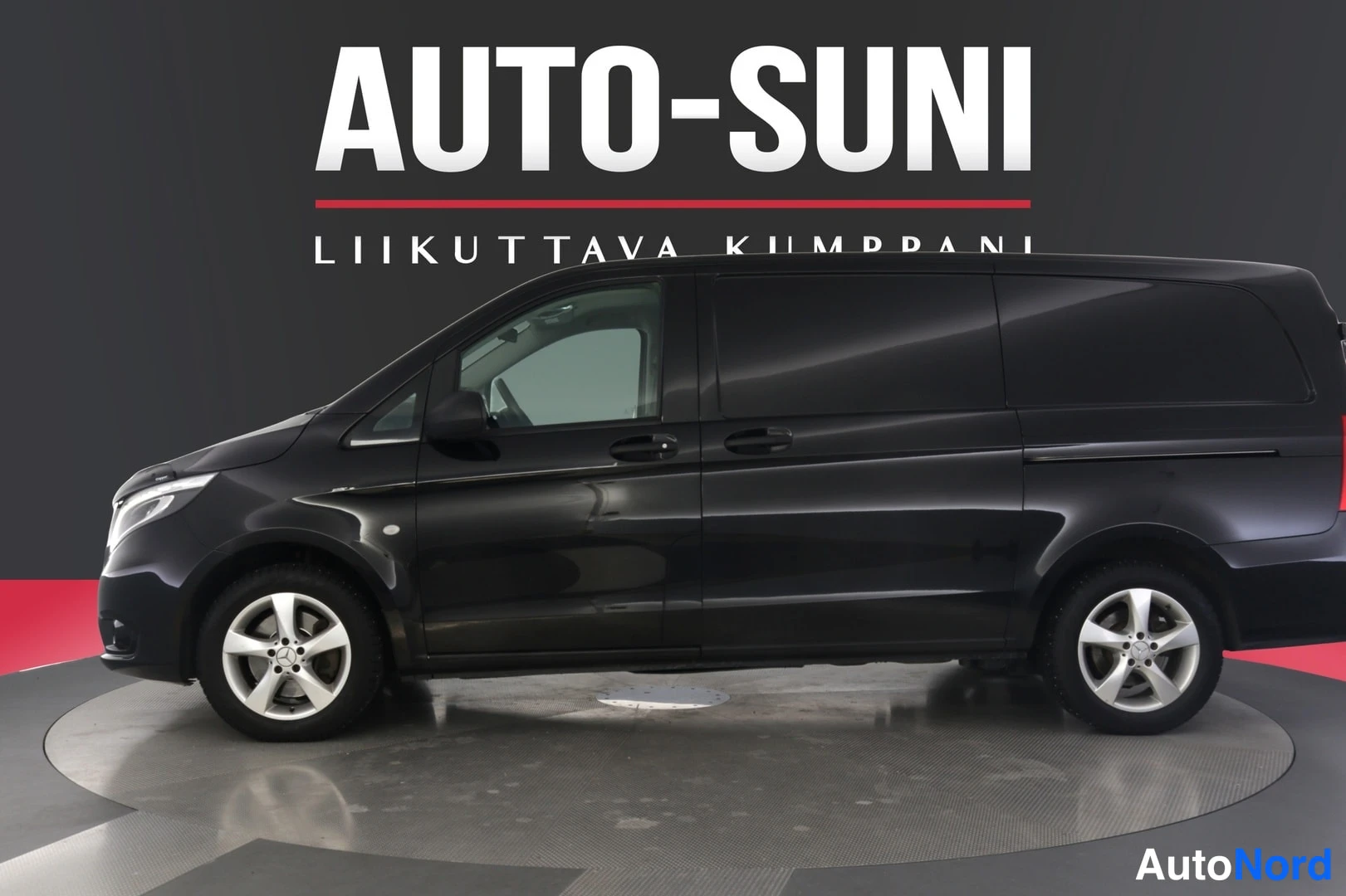 Sivulta: Musta Mercedes-Benz Vito -pakettiauto sivulta kuvattuna studiomaisessa kuvausympäristössä.