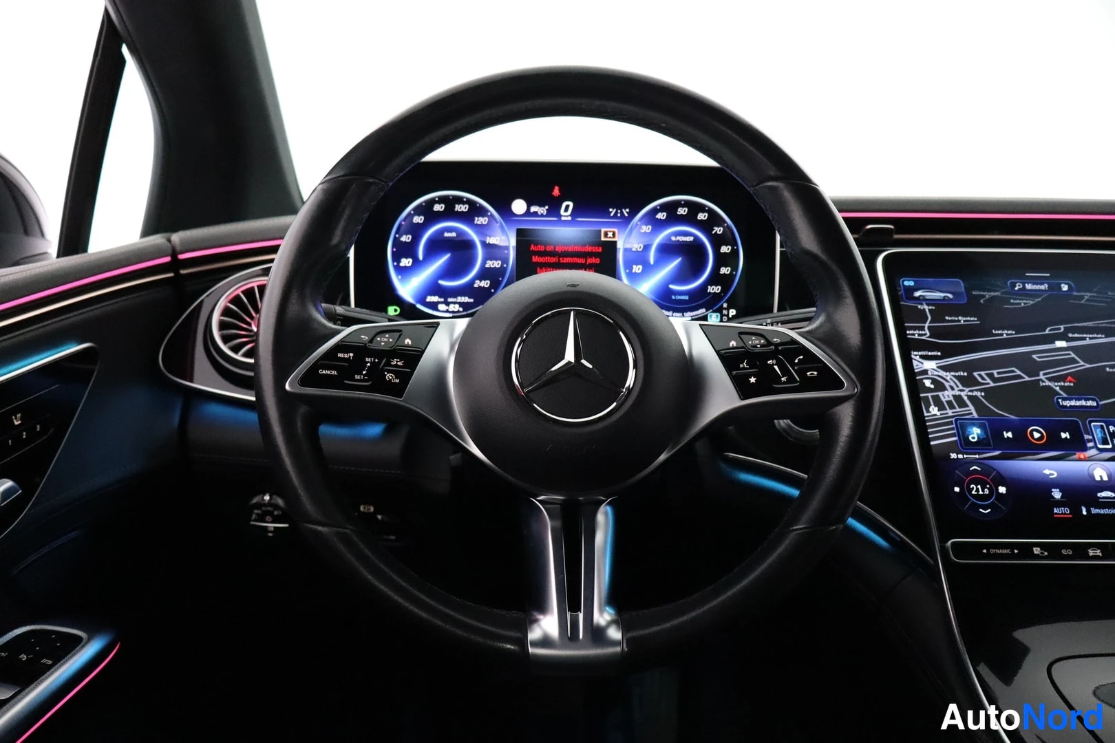Yksityiskohta: Mercedes-Benzin ohjauspyörä ja digitaalinen mittaristo, jonka taustalla on suuri keskinäyttö kartalla.