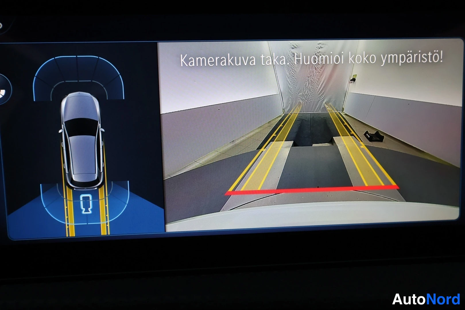 Muu: Takakameran kuva näytöllä tekstillä 'Kamerakuva taka. Huomioi koko ympäristö!' ja kaistaviivoineen.
