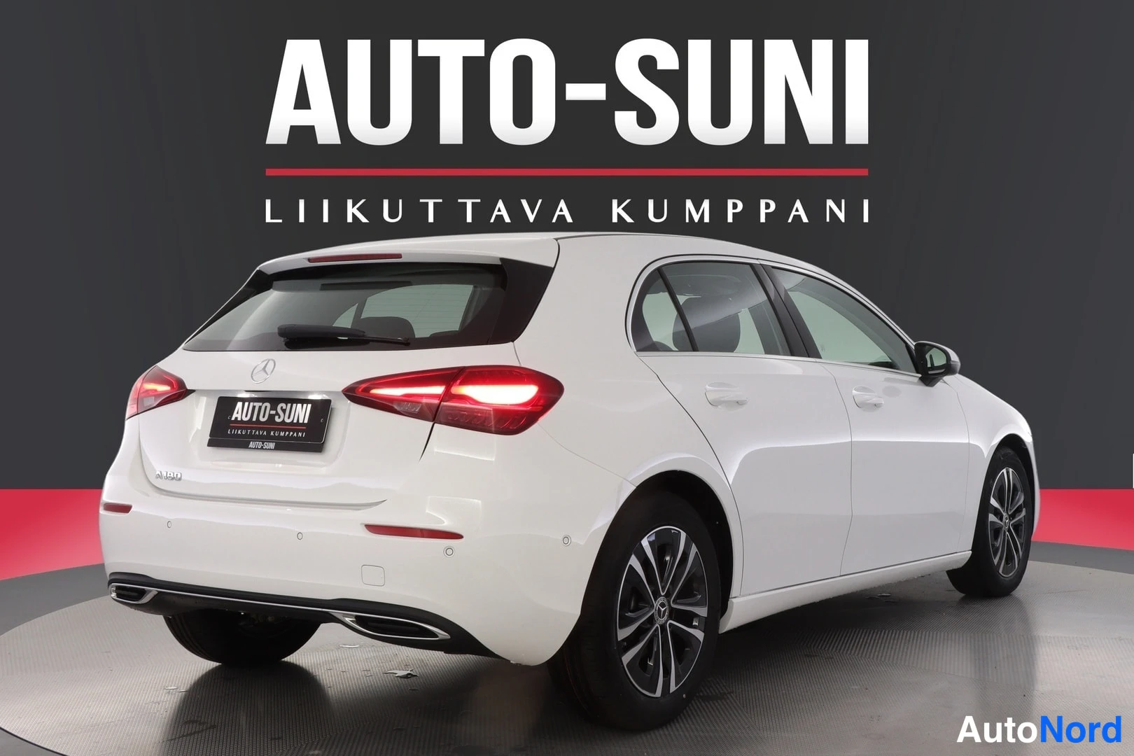 Takaviisto: Mercedes-Benz A -viistoperä takaviistokuva vasemmalta, valkoinen kori, LED-takavalot ja kaksoispakoputket näkyvät.