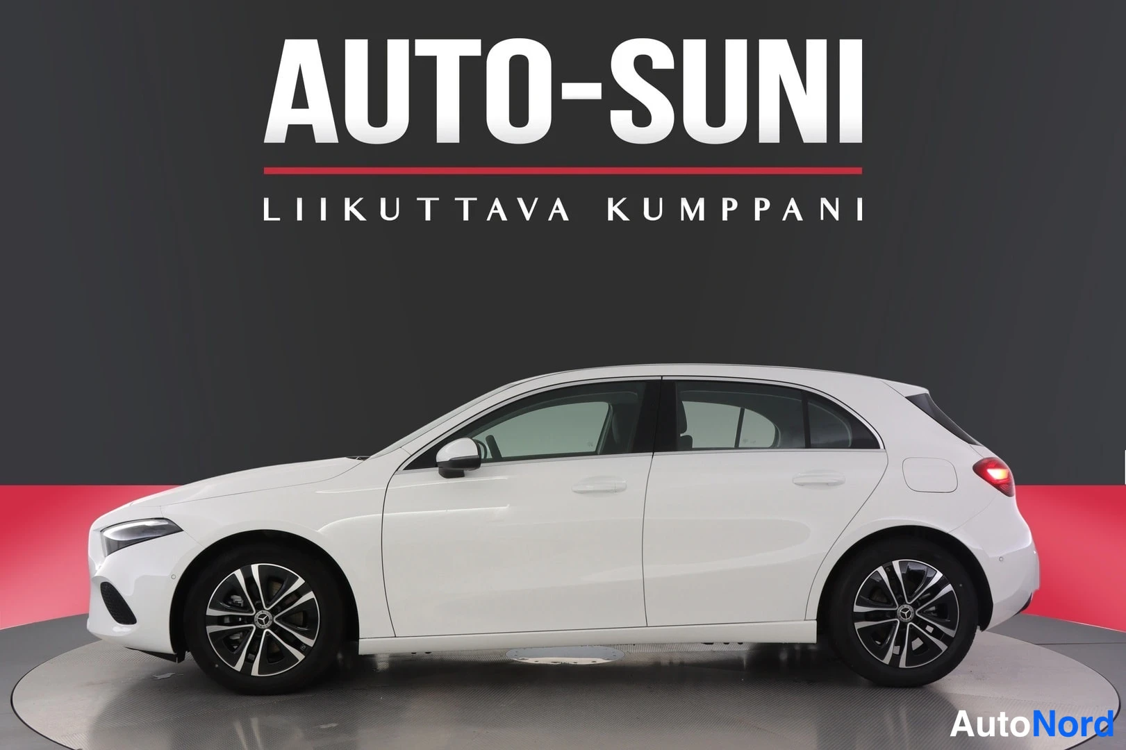 Sivulta: Valkoinen Mercedes-Benz A -henkilöauto studiossa kyljestä kuvattuna, kevytmetallivanteet, AUTO-SUNI-logo taustalla.