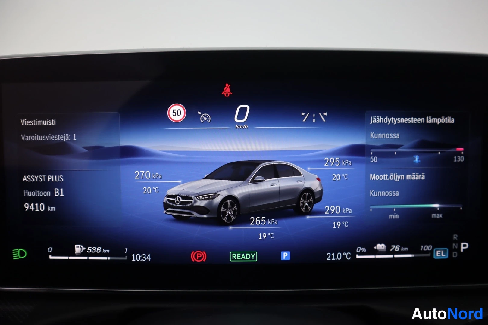 Yksityiskohta: Mercedes-Benzin digitaalinen mittaristo näyttää nopeuden nollana, varoitusvalon (istuinkytkimen), ajoneuvon kuvan ja renkaanpaineet; alareunassa lukee 'ASSYST P
