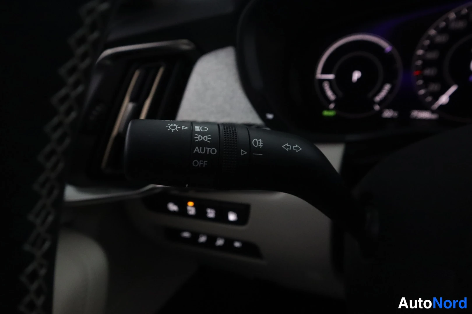 Yksityiskohta: Suuntavilkku- ja valokatkaisijavipu lähikuvassa, merkint AUTO ja OFF, taustalla kojelauta.