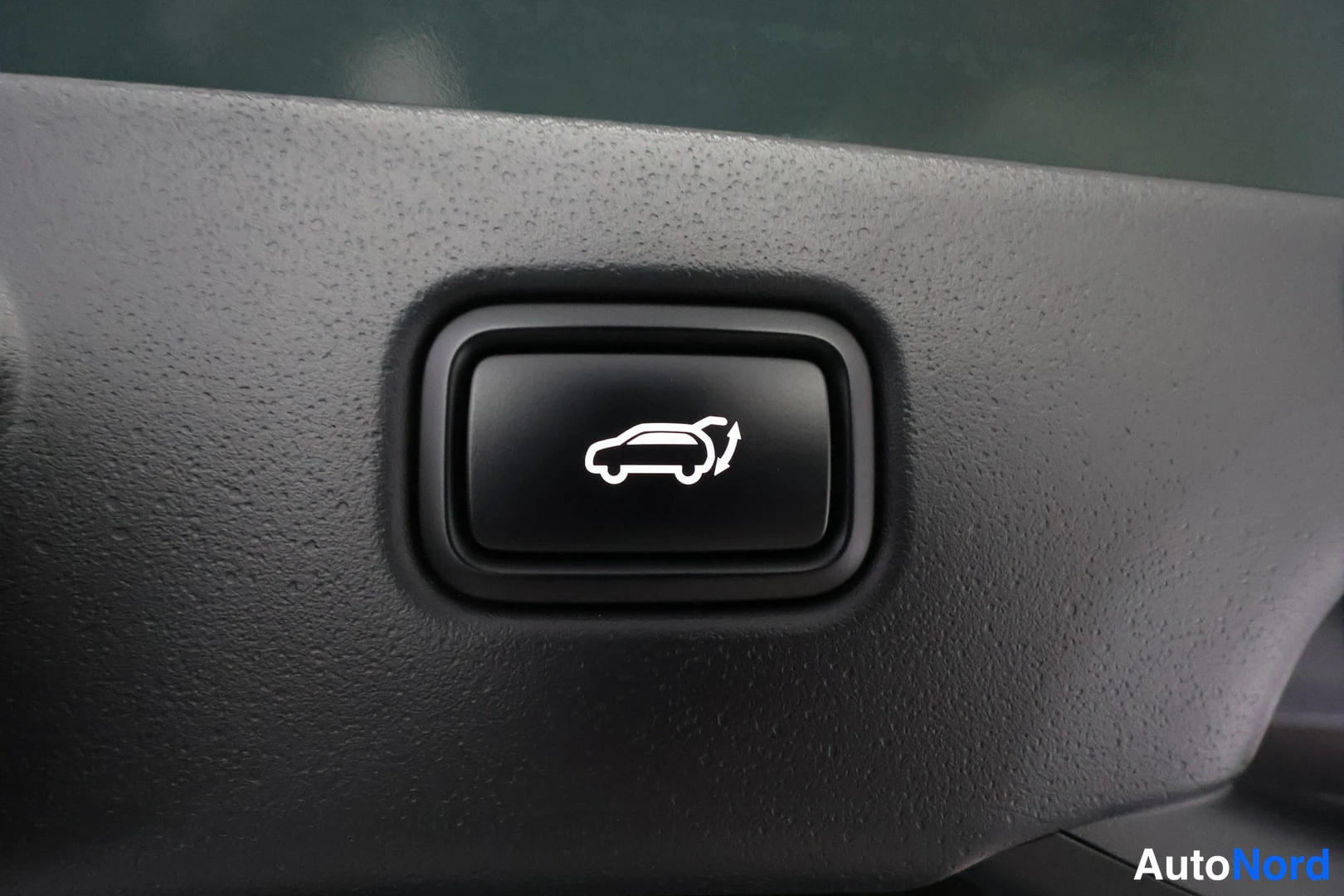 Yksityiskohta: Close-up of a dashboard button with a white icon depicting an open car boot.