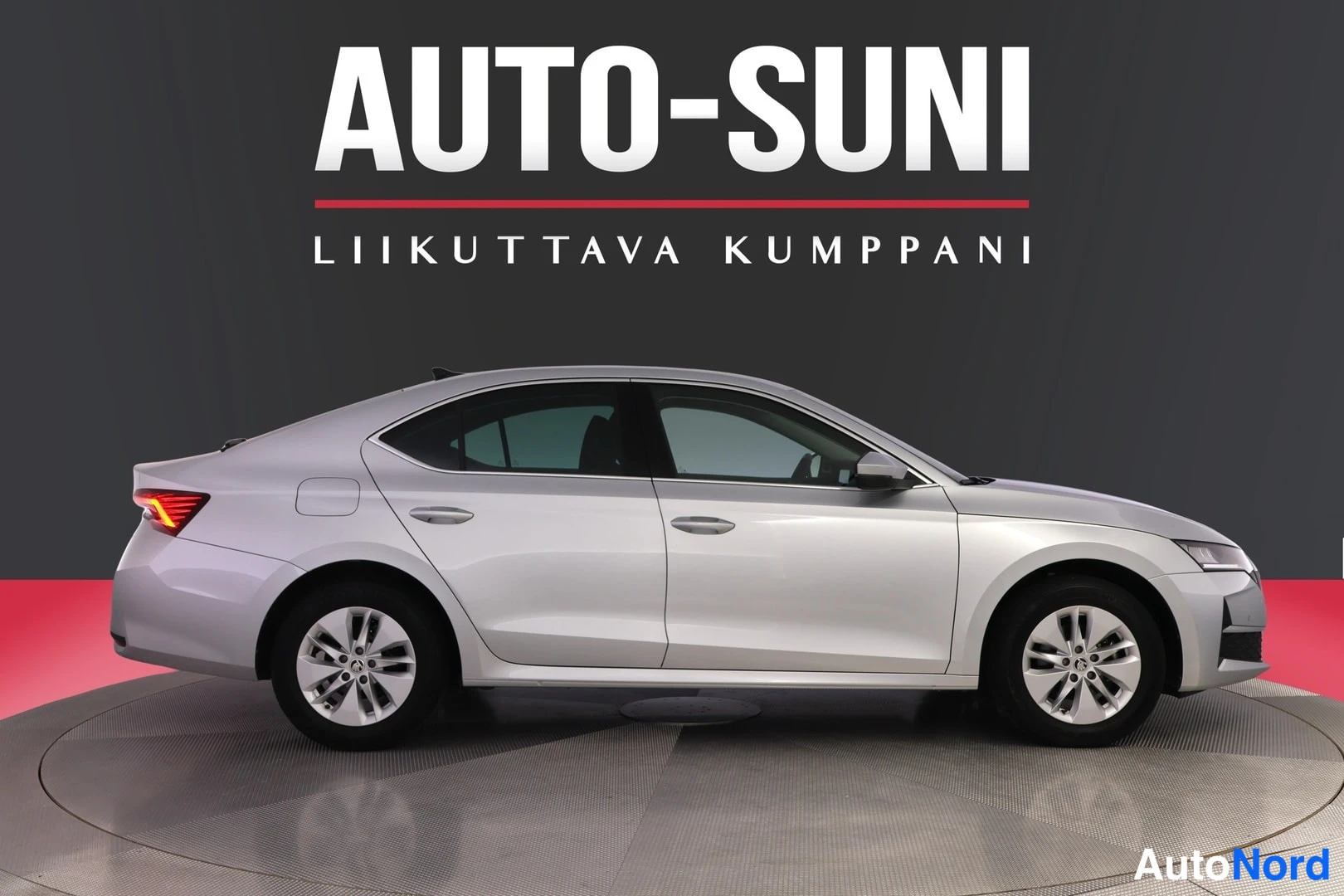 Sivulta: Side profile of the same silver car showing four doors, alloy wheels, and black trim along the window line.