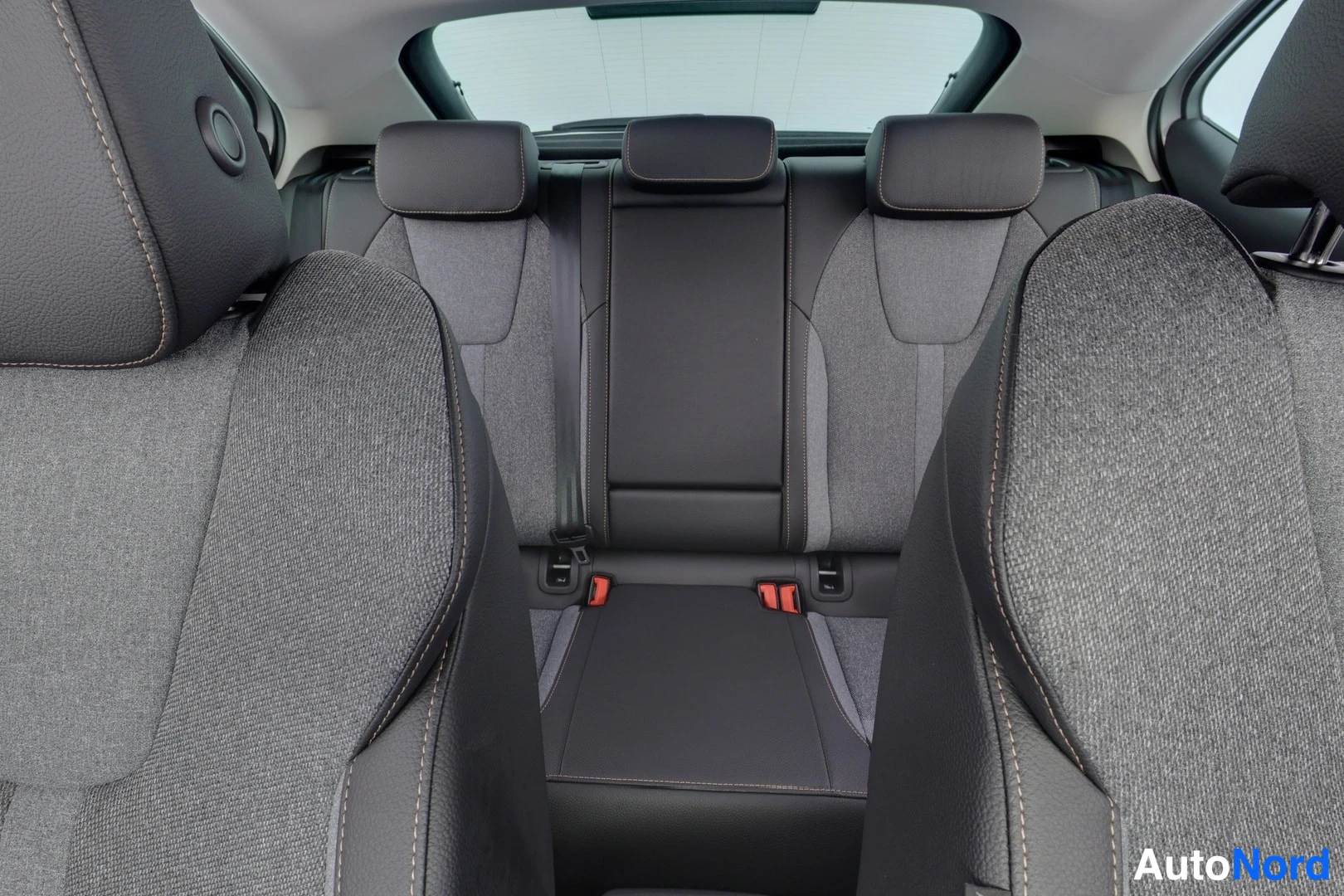 Takaistuimet: View of the rear seating area showing three headrests and grey fabric seat upholstery.