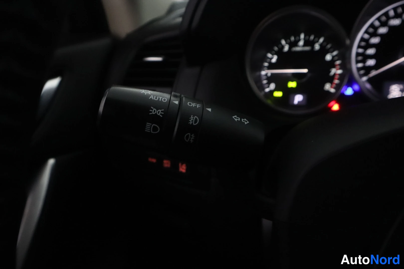 Muu: Valojen kytkimen varsi AUTO- ja OFF-merkinnoilla, taustalla kojelaudan mittarit.