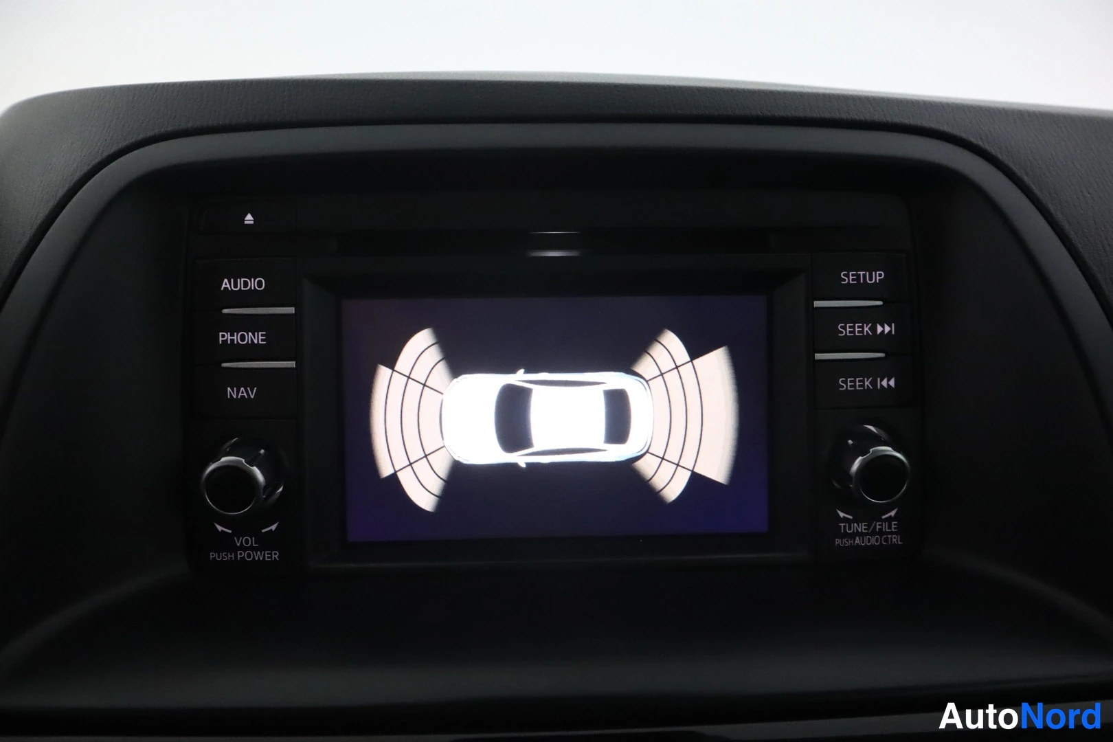 Muu: Infotainment-näyttö näyttää pysäköintitutkan auton ympärillä; näytön reunoilla SETUP-, AUDIO-, PHONE- ja NAV-painikkeet.