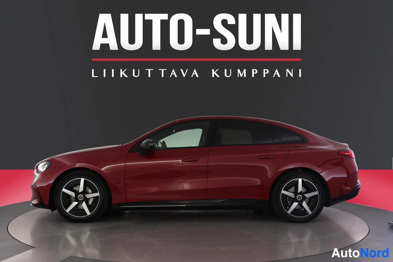 Sivulta: Auton etukolmannelaatarikuva: tummanpunainen sedan profilissa studioimagessa, nokka vasemmalle, mustat vanteet, AUTO-SUNI-logo taustalla.
