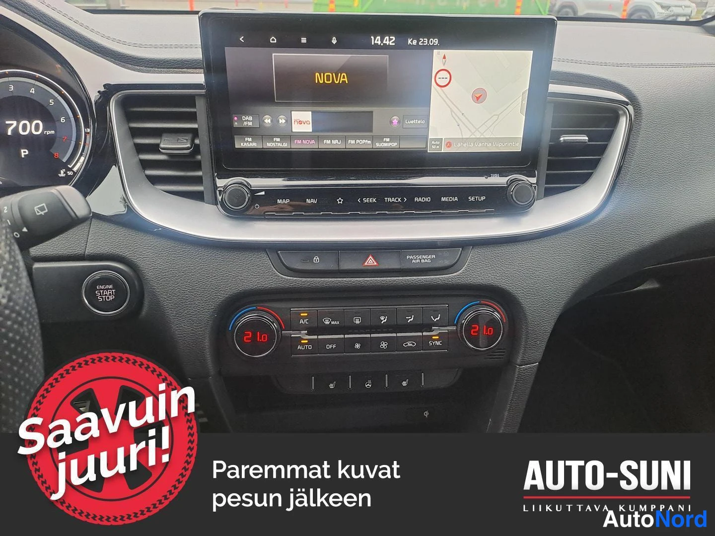 Muu: Auton keskikonsoli: infotainment-näyttö radiokanavineen ja karttanimellä NOVA, alla kaksivyöhykeilmastointi asetuksella 21,0 asti. Engine Start Stop -nappi näky