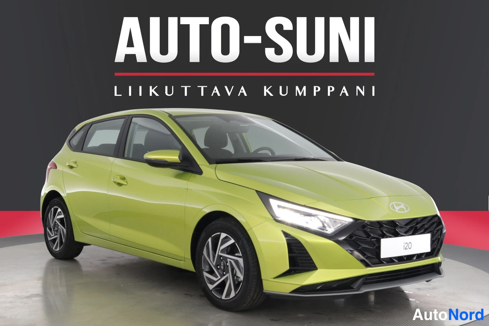 Etuviisto, nokka oikealle: Keltavihreä Hyundai i20 -henkilöauto kuvattu kolmanneltä edestä, nokka oikealle; näkyvät etusäleikkö, ajovalot ja keulamerkki.