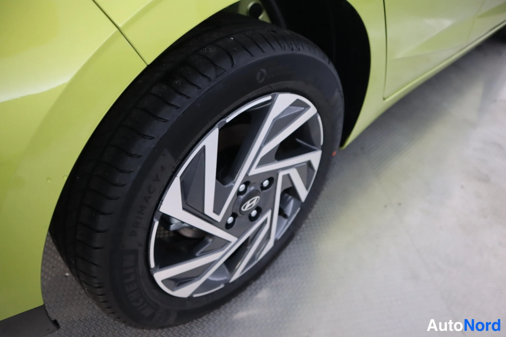 Sivulta: Keltavihreän auton etupyörä lähikuvassa; Michelin Primacy -rengas ja kaksivärinen helppovanteinen alloy-vanne.
