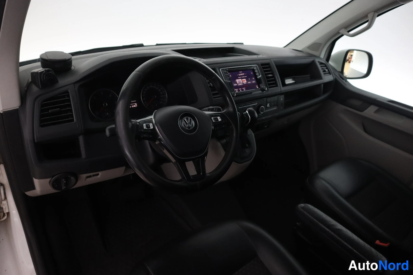 Muu: Kojelauta ja musta VW-ohjauspyörä suoraan edestä, keskirivillä näyttö ja ilmastointisäätimet.