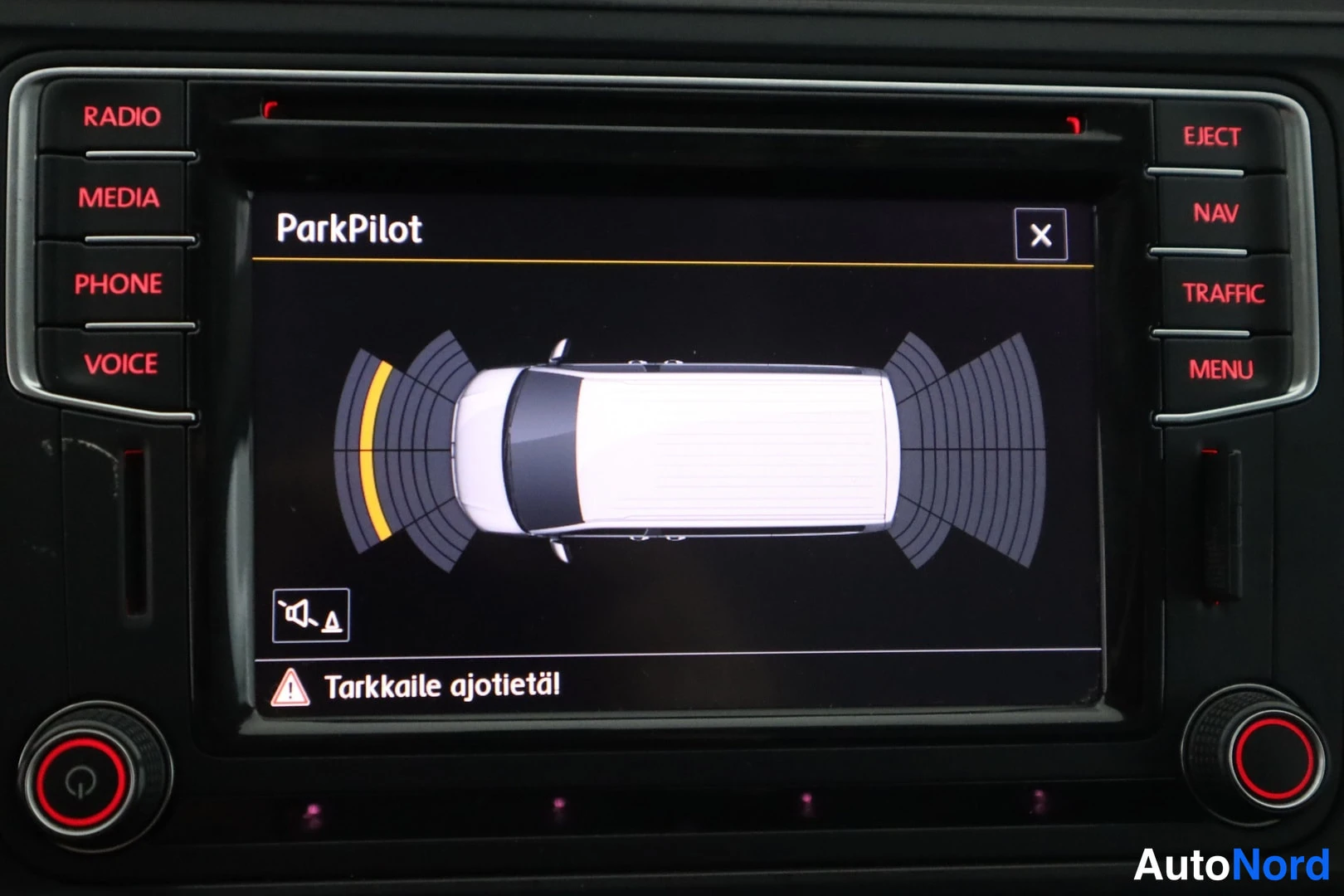 Yksityiskohta: Radionäytössä ParkPilot-törmäysvaroituksen ajoneuvografiikka ja teksti Tarkkaile ajotietä.