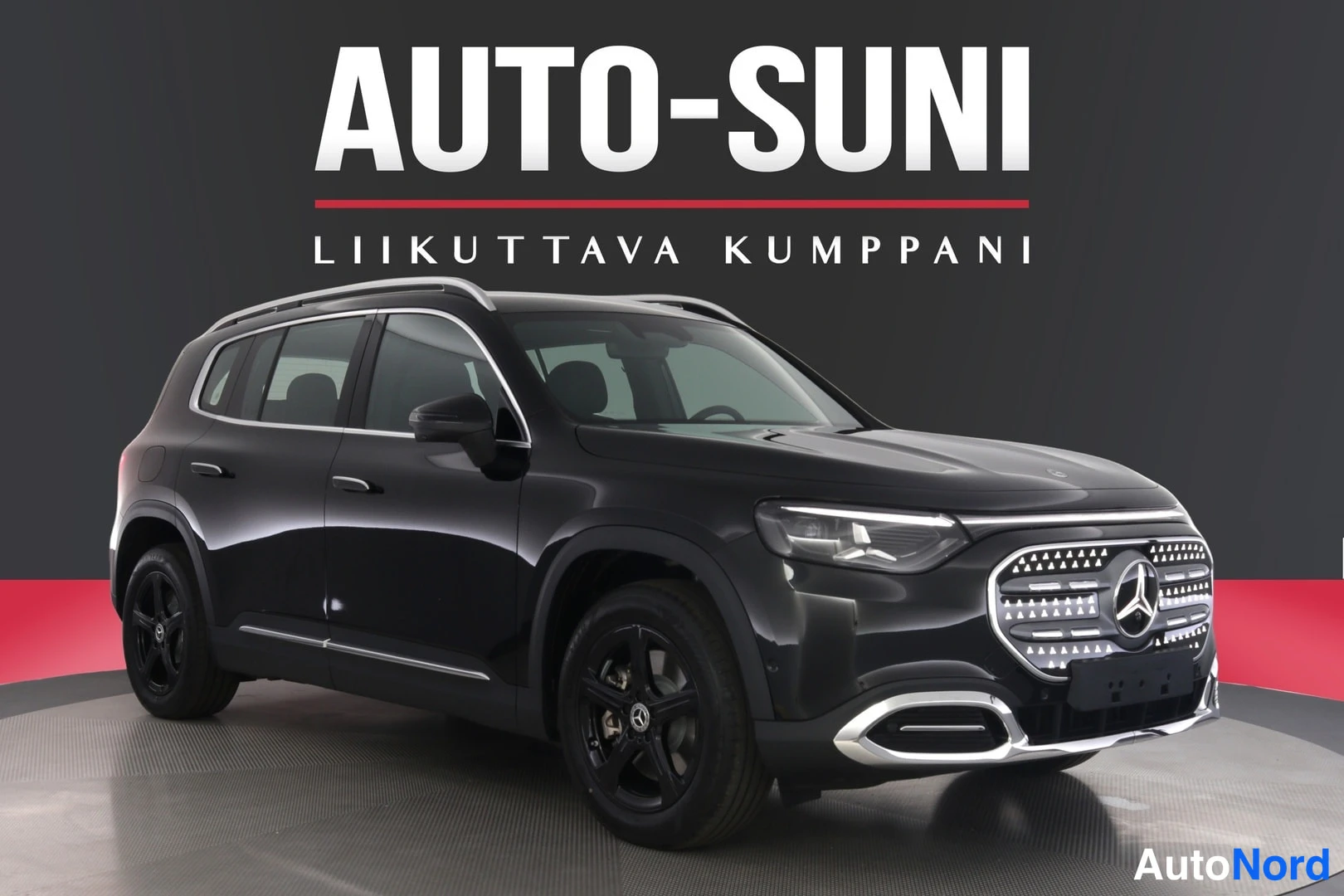 Etuviisto, nokka oikealle: Musta Mercedes-Benz GLB 350 4MATIC -maasturissa etuviistöltä oikealta, etusäleikkö ja ajovalot näkyvissä, mustat kevytmetallivanteet ja kattokaaret.