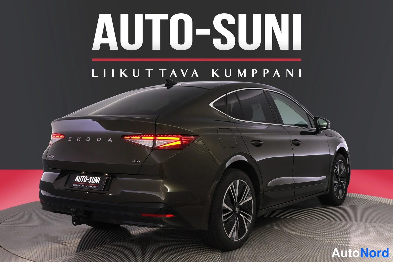 Takaviisto: Skoda Enyaq takakulmakuva; takavalot, SKODA-teksti ja 85x-merkintä näkyvät, tummanruskea kori.