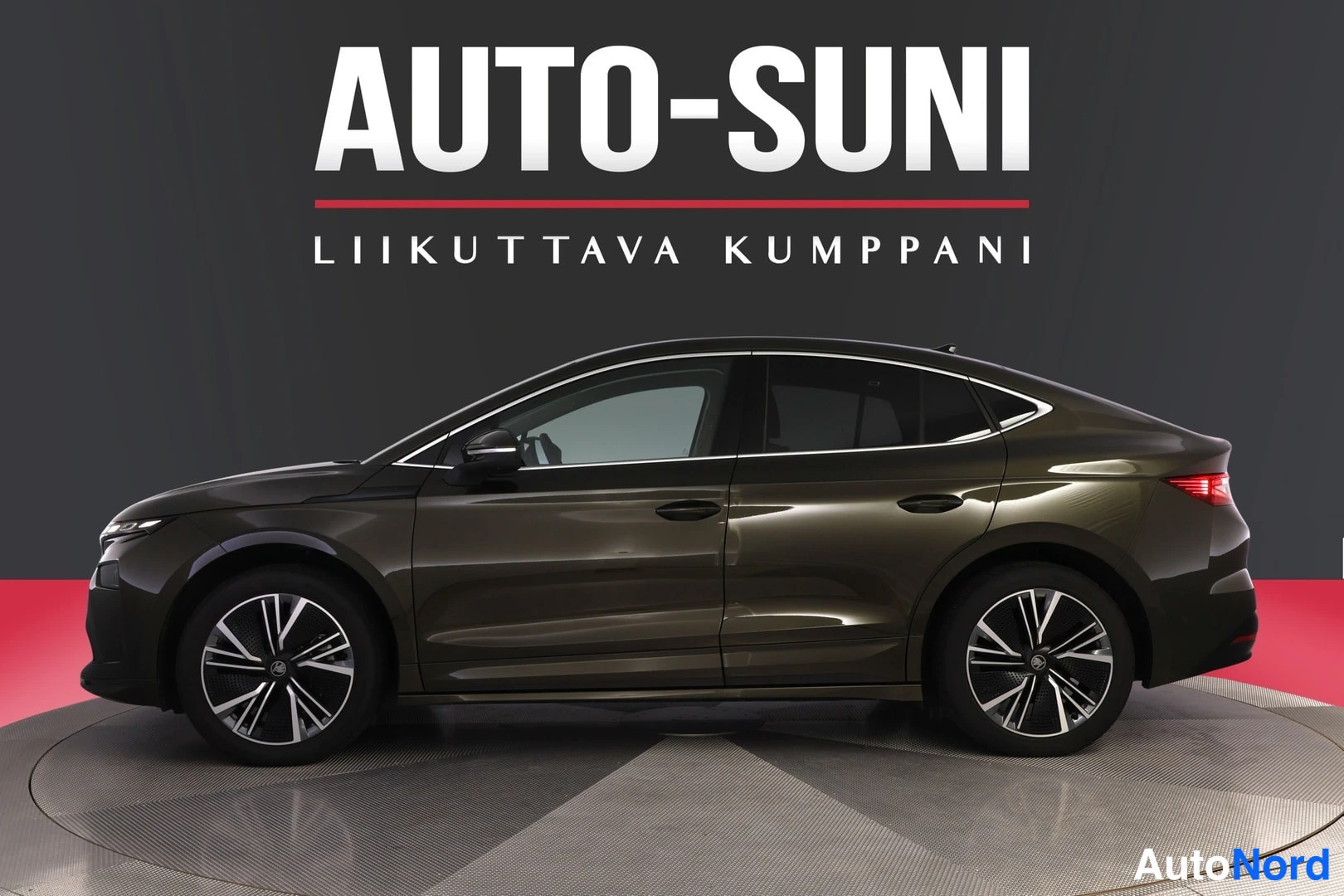 Sivulta: Tummanruskea coupémaiset SUV henkilöauto sivulta etukolmasosa, valokuvausstudion harmaata taustaa vasten, AUTO-SUNI-logo kuvan yläosassa.