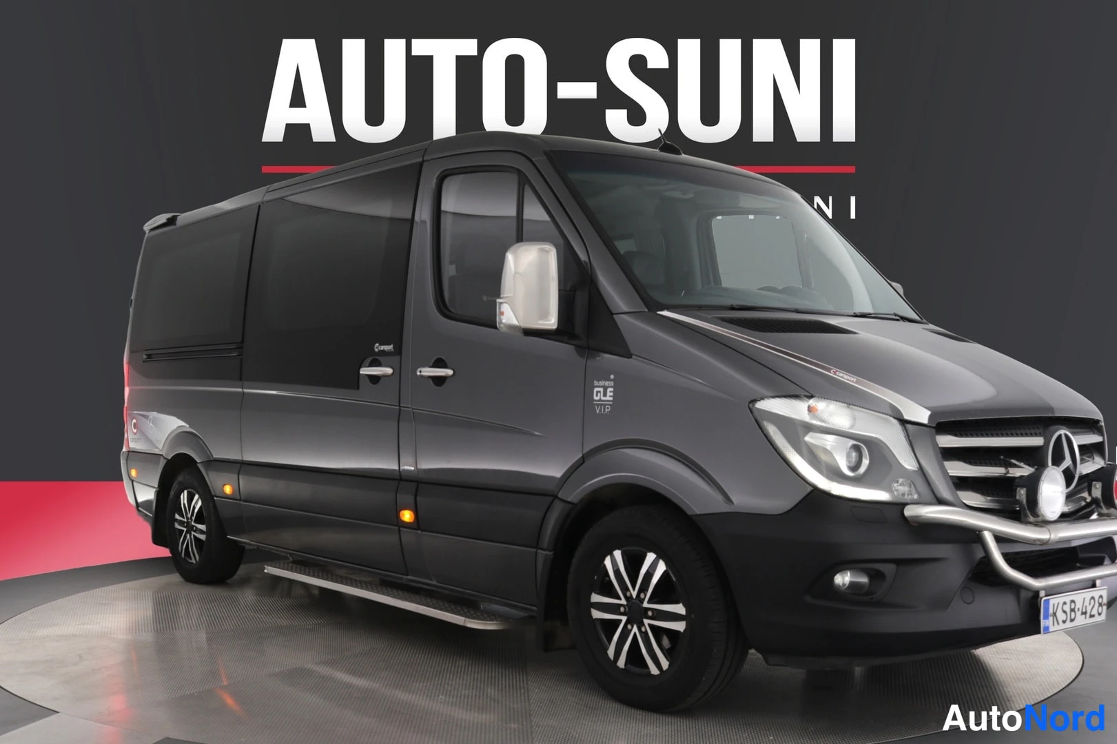 Etuviisto, nokka oikealle: Tummanharmaa Mercedes-Benz Sprinter -pakettiauto vinosta edestä oikealta kuvattuna näyttely-ympäristössä.