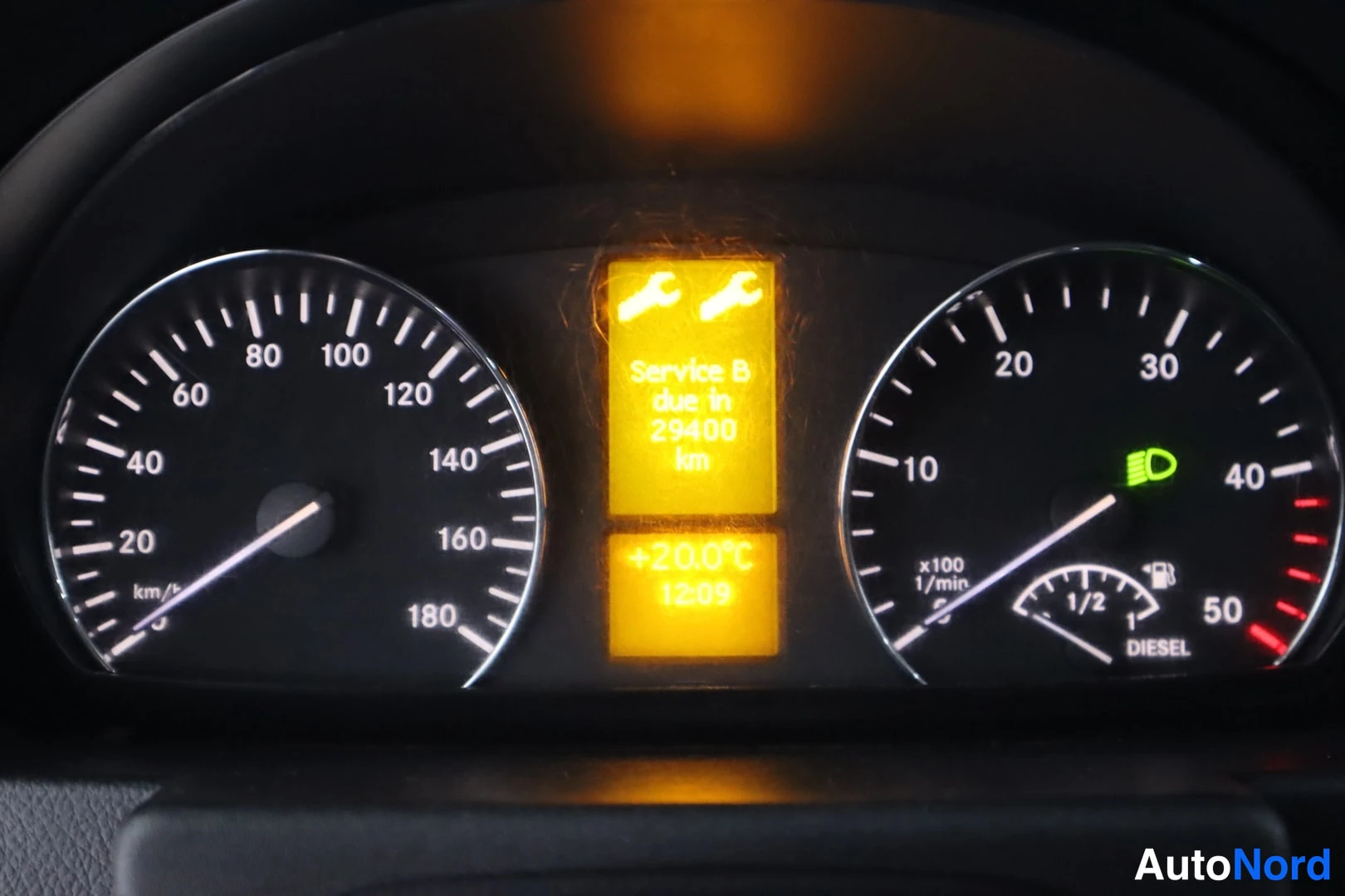 Yksityiskohta: Mittaristo: nopeusmittari 0–180 km/h, kierrosmittari x100 1/min, palvelukehote 'Service B due in 29400 km', lämpötila +20.0°C, kellonaika 1209, polttoainemittar