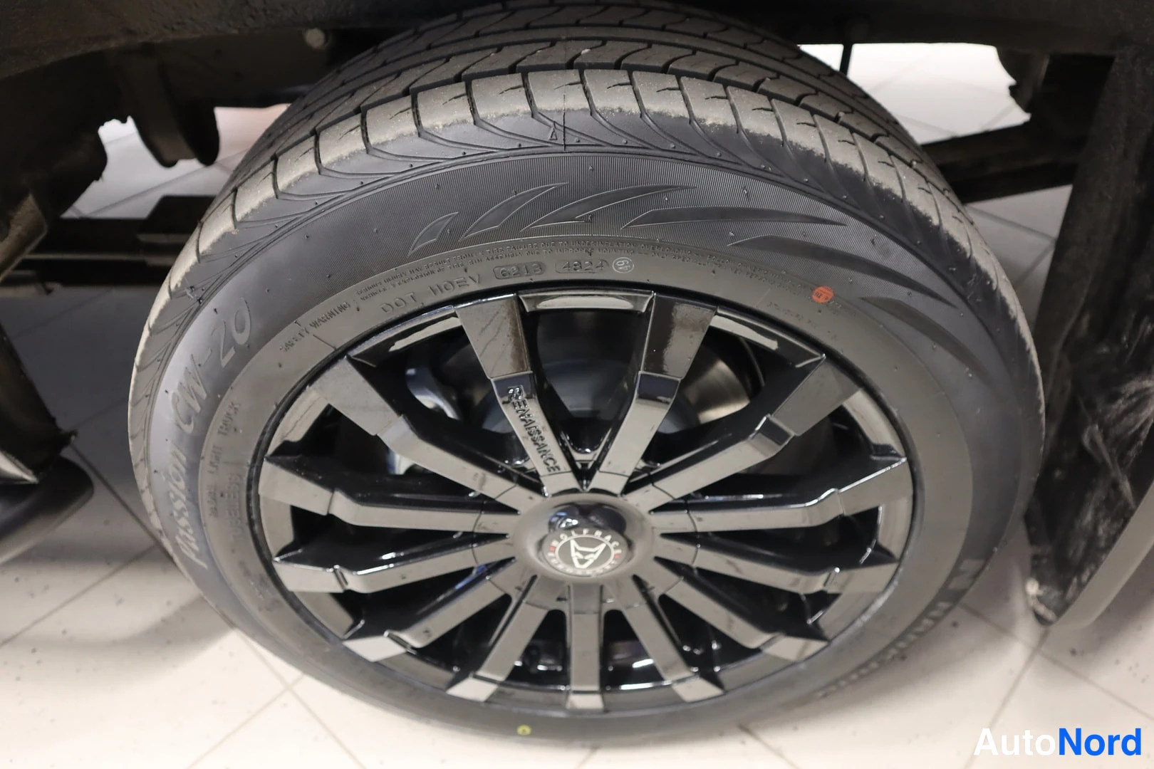 Yksityiskohta: Mustan monipuolisen kevytmetallivanteen lähikuva; renkaankyljessä näkyvät tekstit 235/55R19 111W M+S ja Passion CW-20.