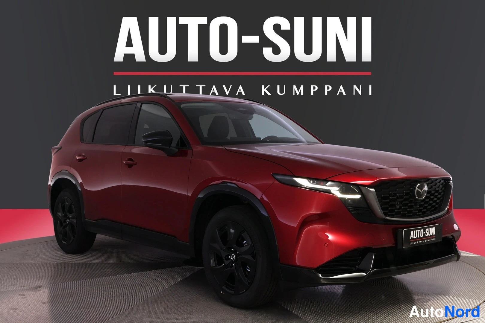 Etuviisto, nokka oikealle: Punainen Mazda CX-5 kulmasta edestä oikealta kuvattuna, mustat vanteet ja Auto-Suni-tunnus taustalla.