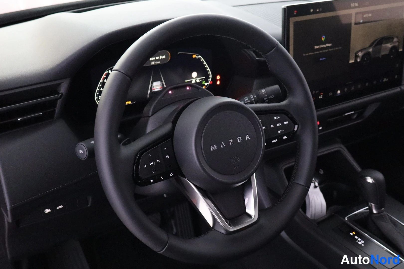 Muu: Mazda-ohjauspyörä ohjaamossa, taustalla digitaalinen mittaristo ja infotainment-näyttö