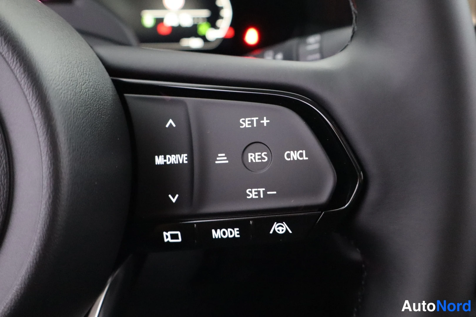 Muu: Lähikuva ohjauspyörän napeista: MI-DRIVE, vakionopeudensäädin (SET+, RES, CNCL, SET−), MODE ja ajopalkin symboli.