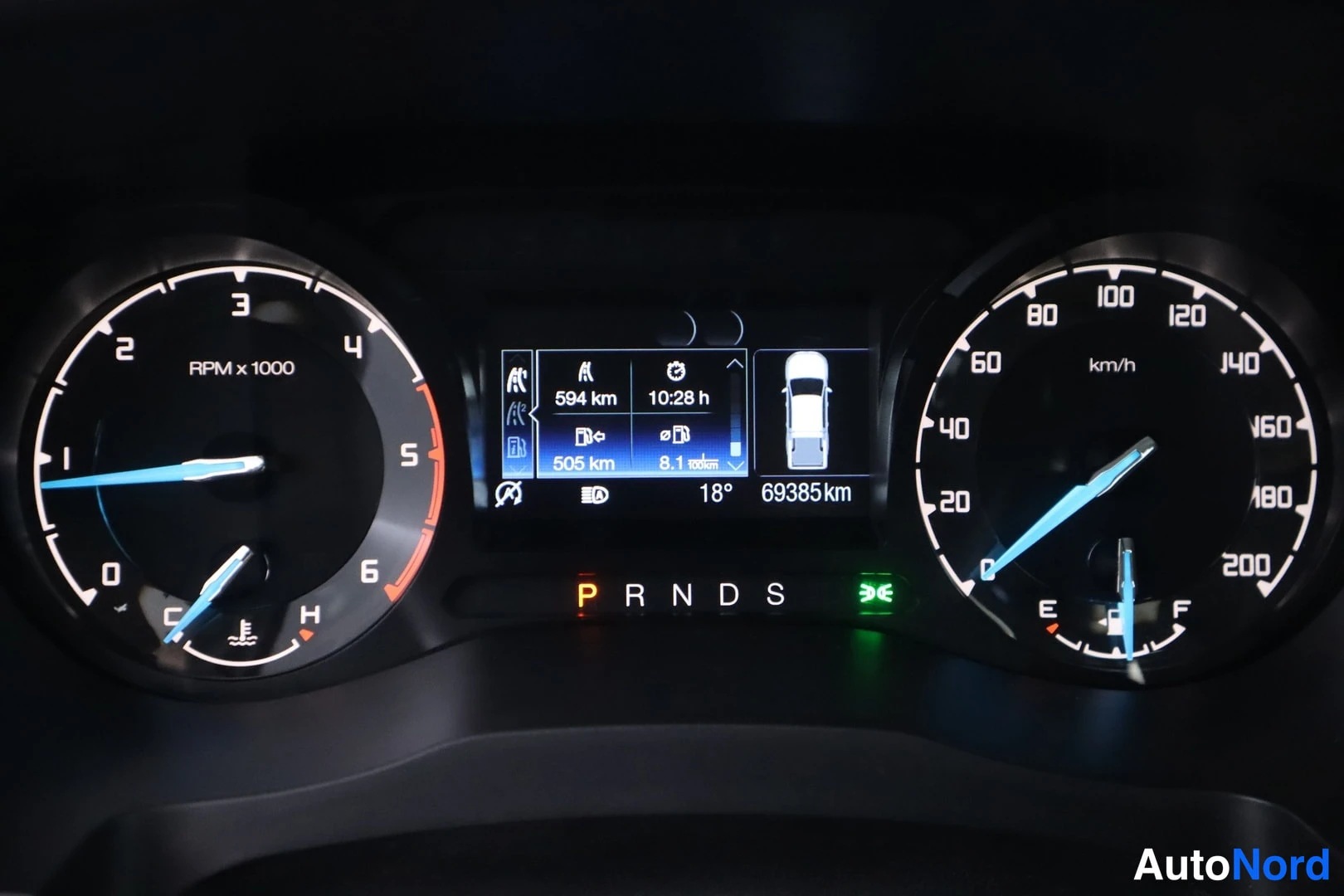 Yksityiskohta: Kojelauta: digitaalinäyttö näyttää 69385 km, vaihde P ja 18 °C:n lämpötilan.