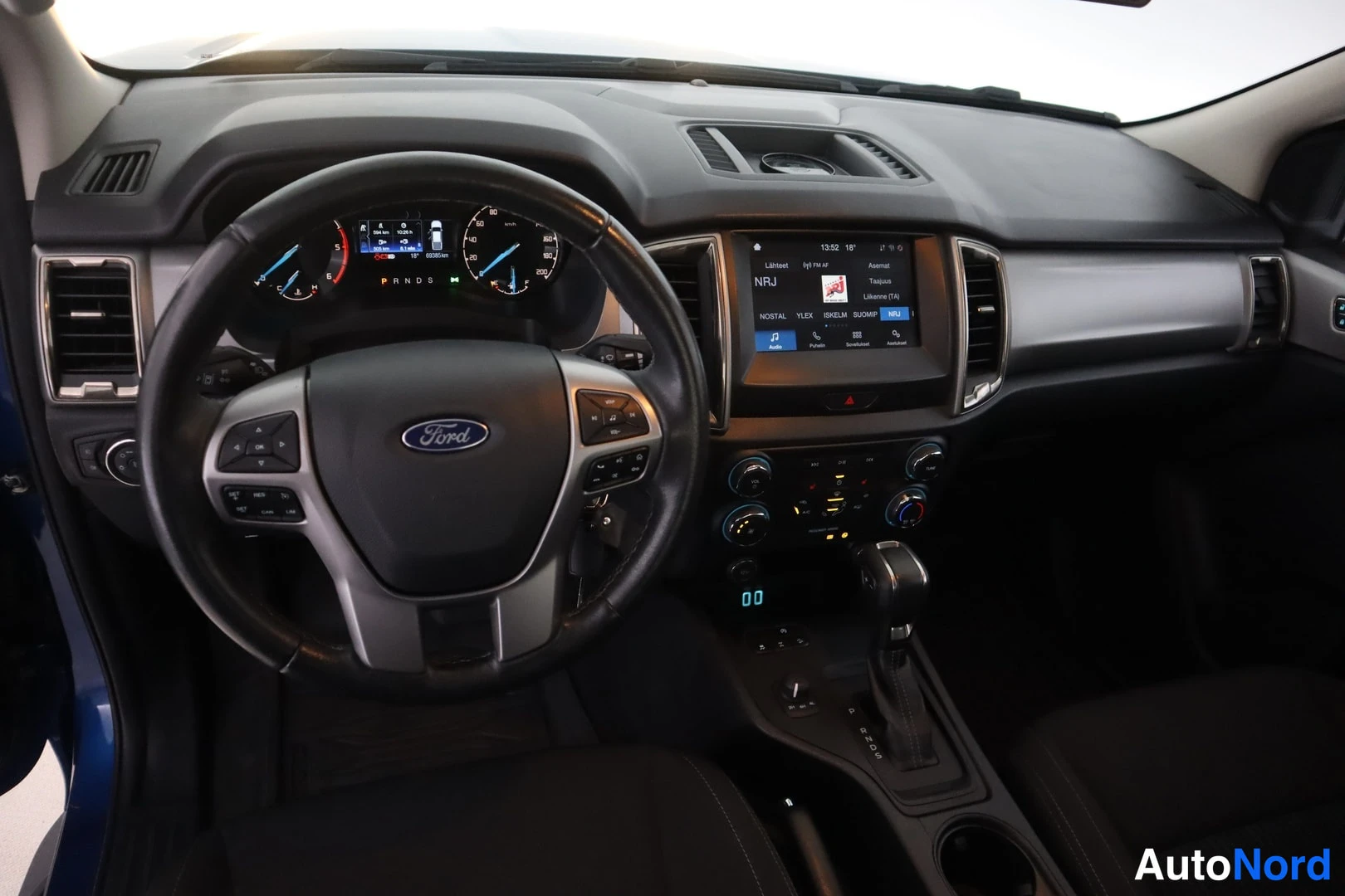 Yksityiskohta: Ohjaamo vasemmalta: Ford-merkkinen ohjauspyörä, mittaristo ja keskikonsolin kosketusnäyttö, automaattivaihteen valitsin ja nappiryhmät.