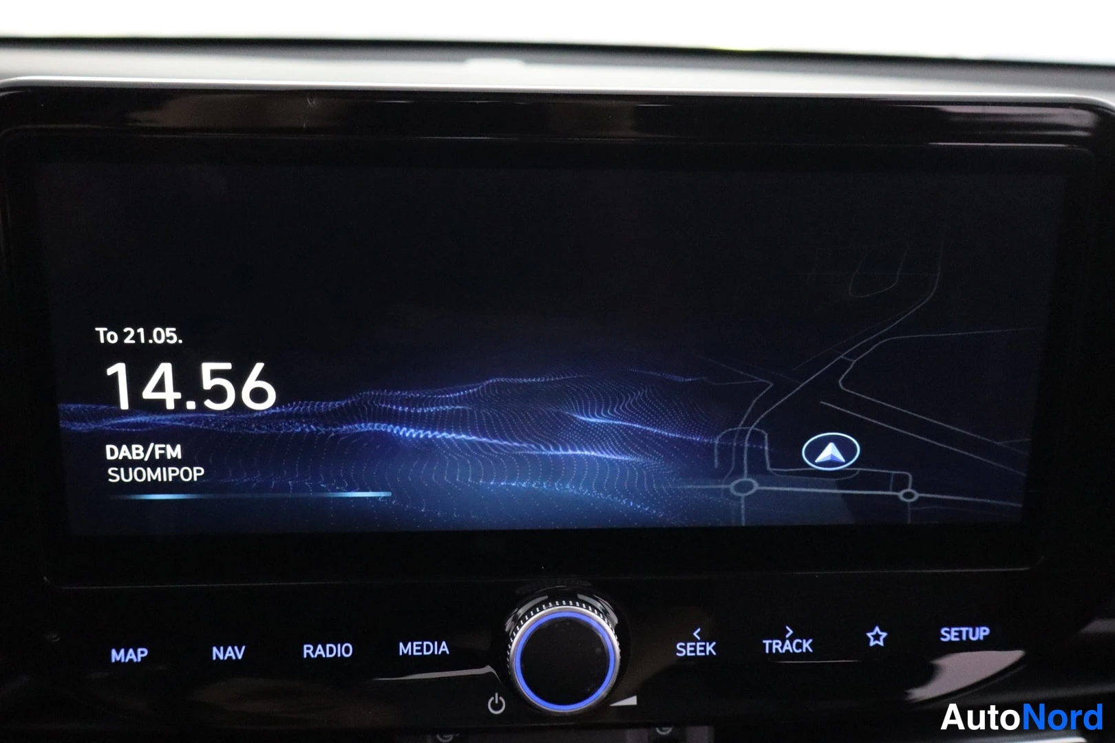 Muu: Infotainment-näyttö ilta-aiheisella aloitusnäkymällä, jossa lukee kello 14.56, To 21.05. ja DAB/FM Suomipop, sekä MAP-, NAV-, RADIO-, MEDIA-, SEEK-, TRACK- ja S