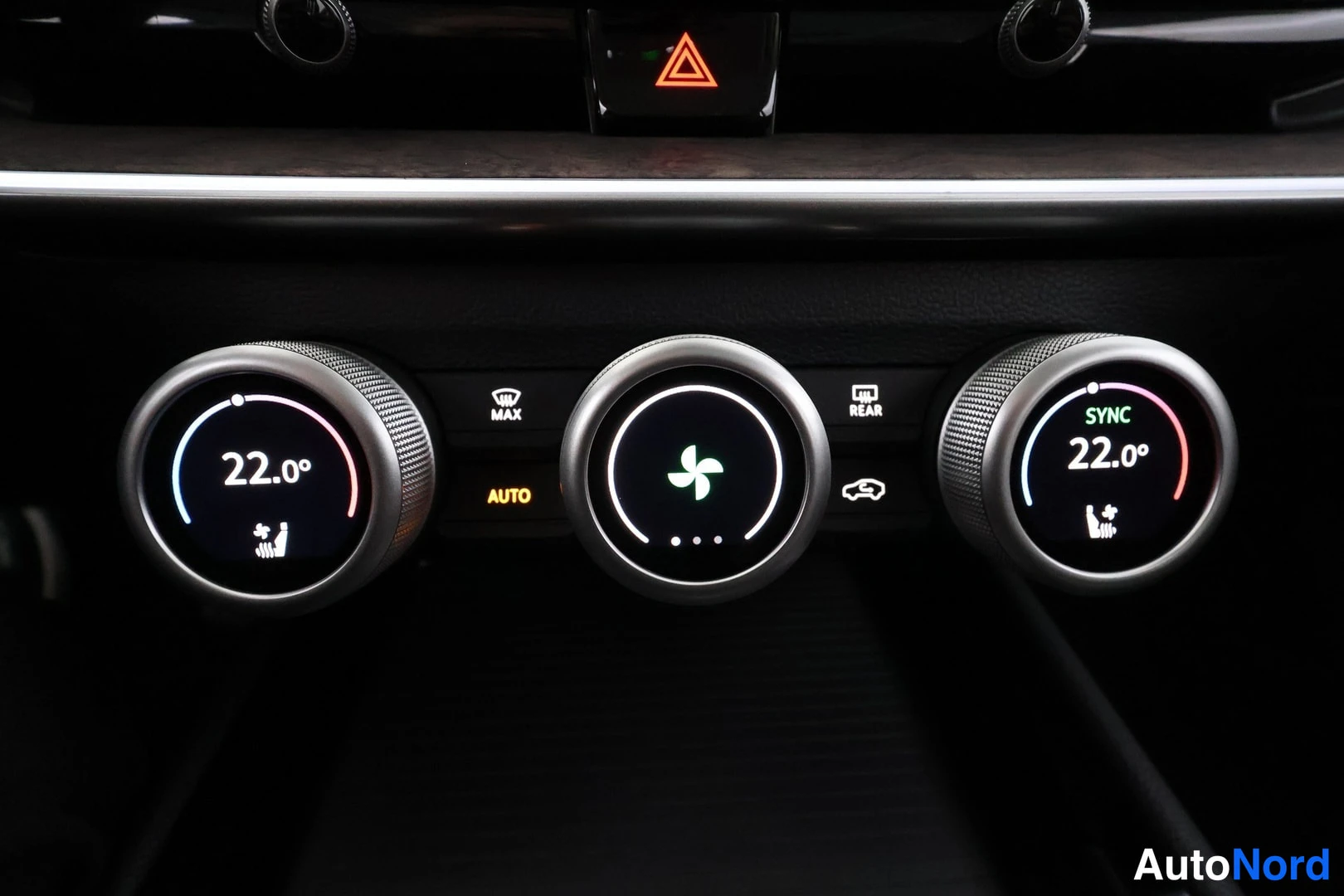 Muu: Close-up of the dashboard's centre console: three illuminated rotary climate control knobs, the left and right ones reading 22.0° and the middle one showing a f