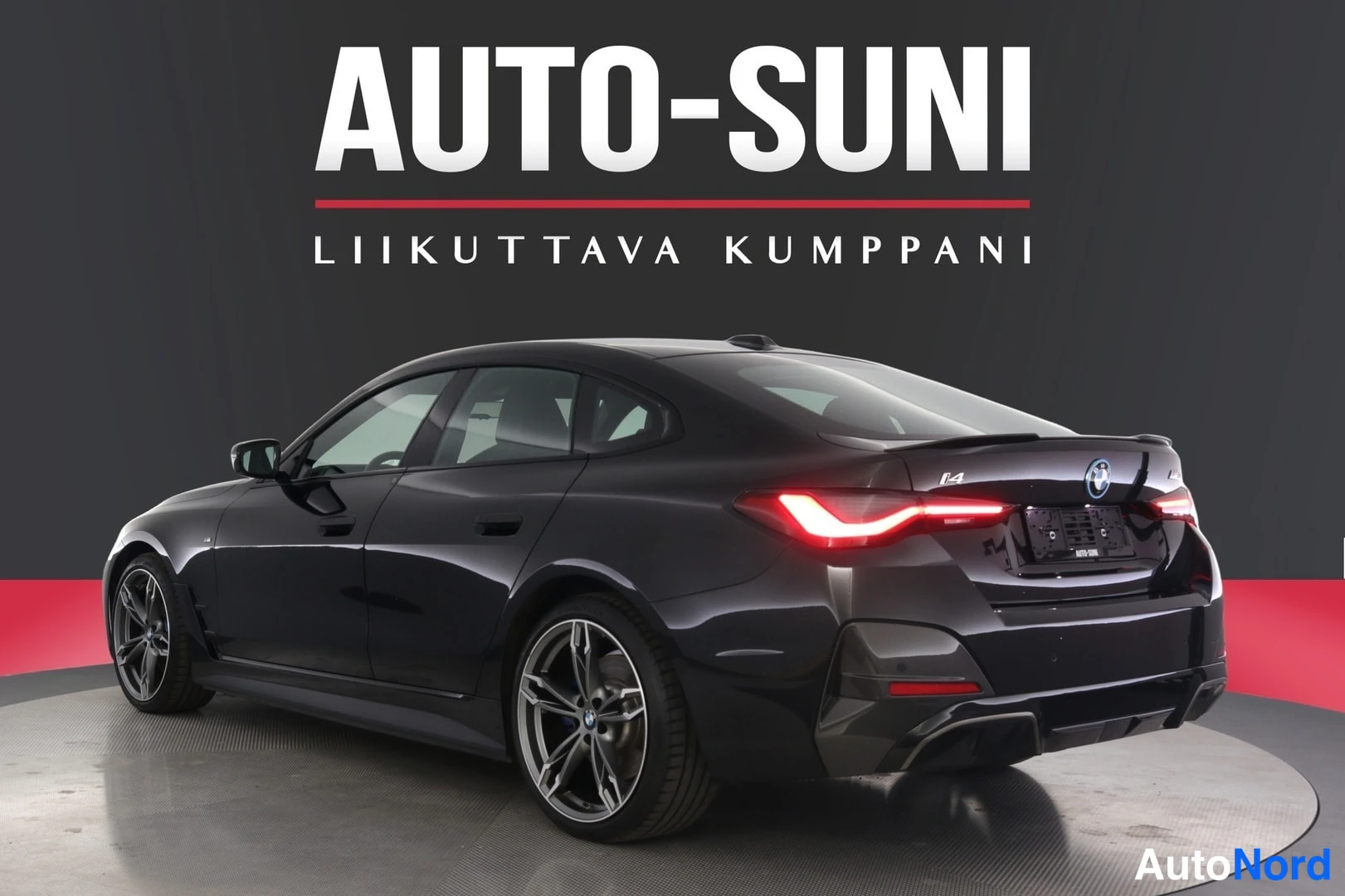 Takaviisto: Musta BMW i4 -sedan takaviistokulma studiosta, takavalot ja i4-merkki näkyvissä.