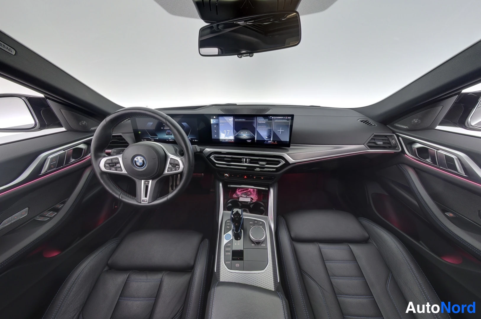 Muu: Mustien nahkapenkkien ympäröimä BMW i4:n ohjaamo, jossa näkyy ohjauspyörä ja kosketusnäytöt