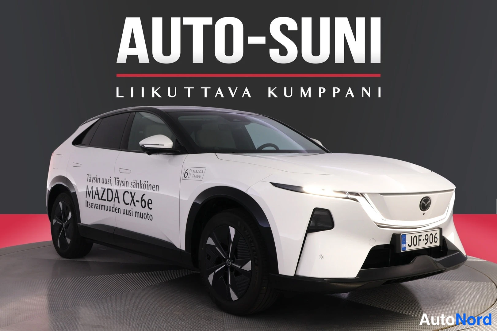 Etuviisto, nokka oikealle: Valkoinen Mazda CX-6e -porrasperä etukulmasta, keula vasemmalla, Auto-Suni-taustalla