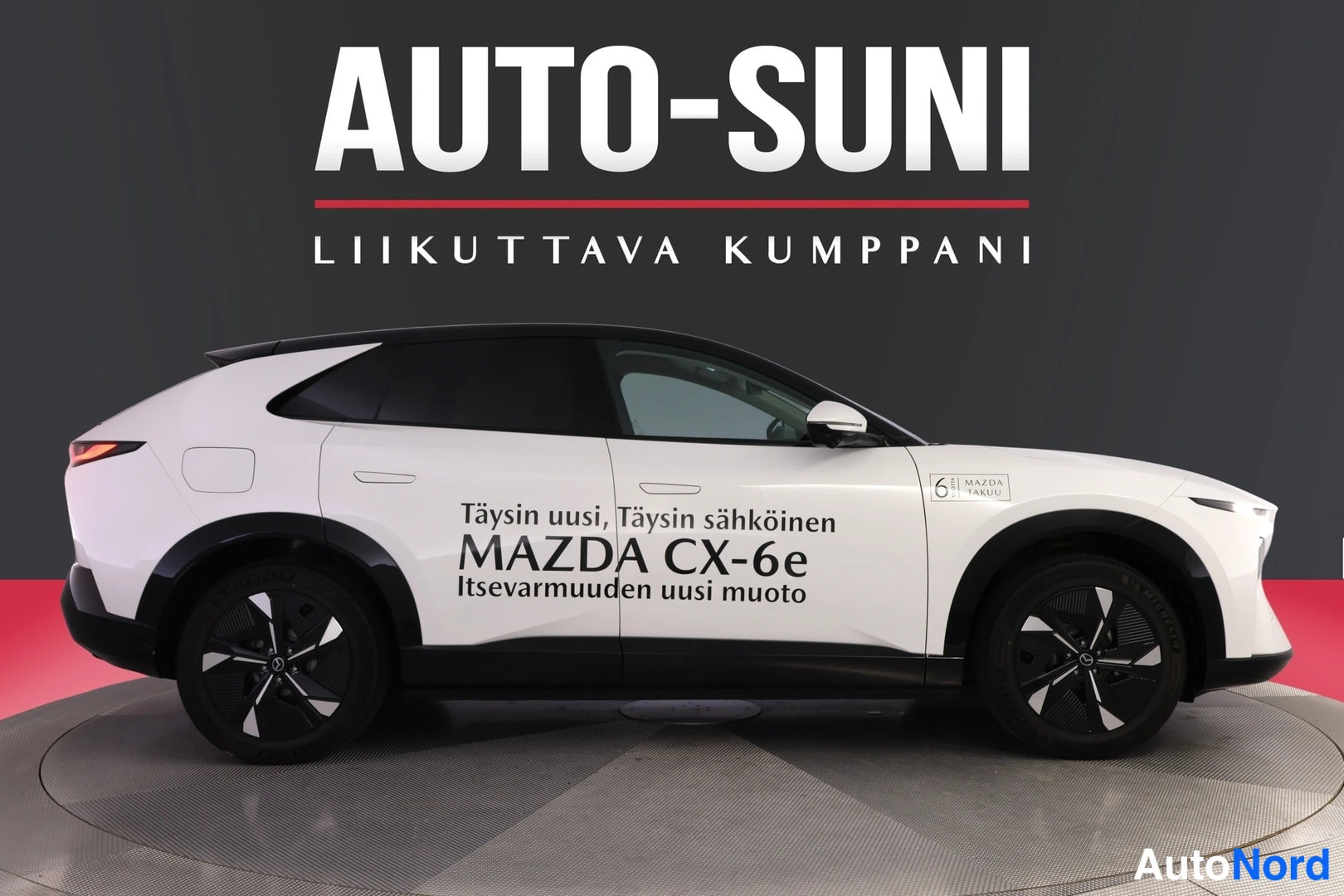 Sivulta: Valkoinen Mazda CX-6e -porrasperä sivusta, korin kyljessä mainosteksti