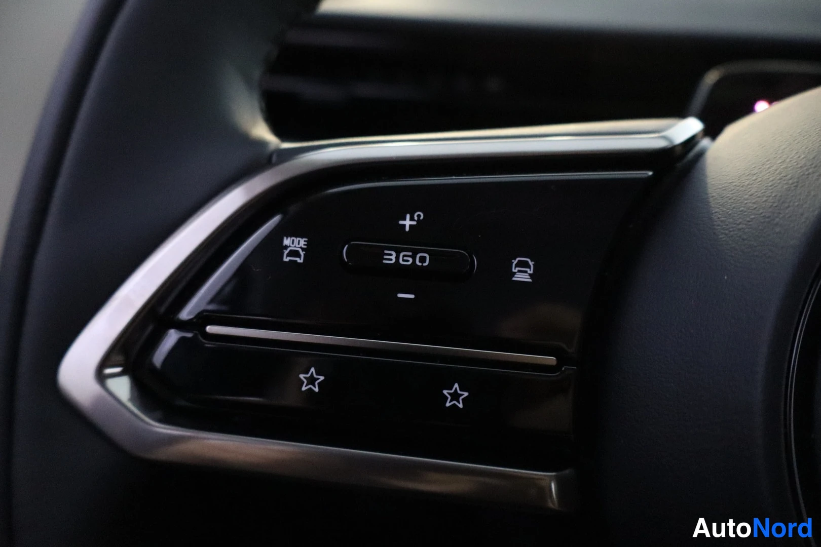 Yksityiskohta: Close-up of the right-side controls on the steering wheel featuring buttons for camera view adjustment ('360'), lane assist monitoring (car icon), and volume co