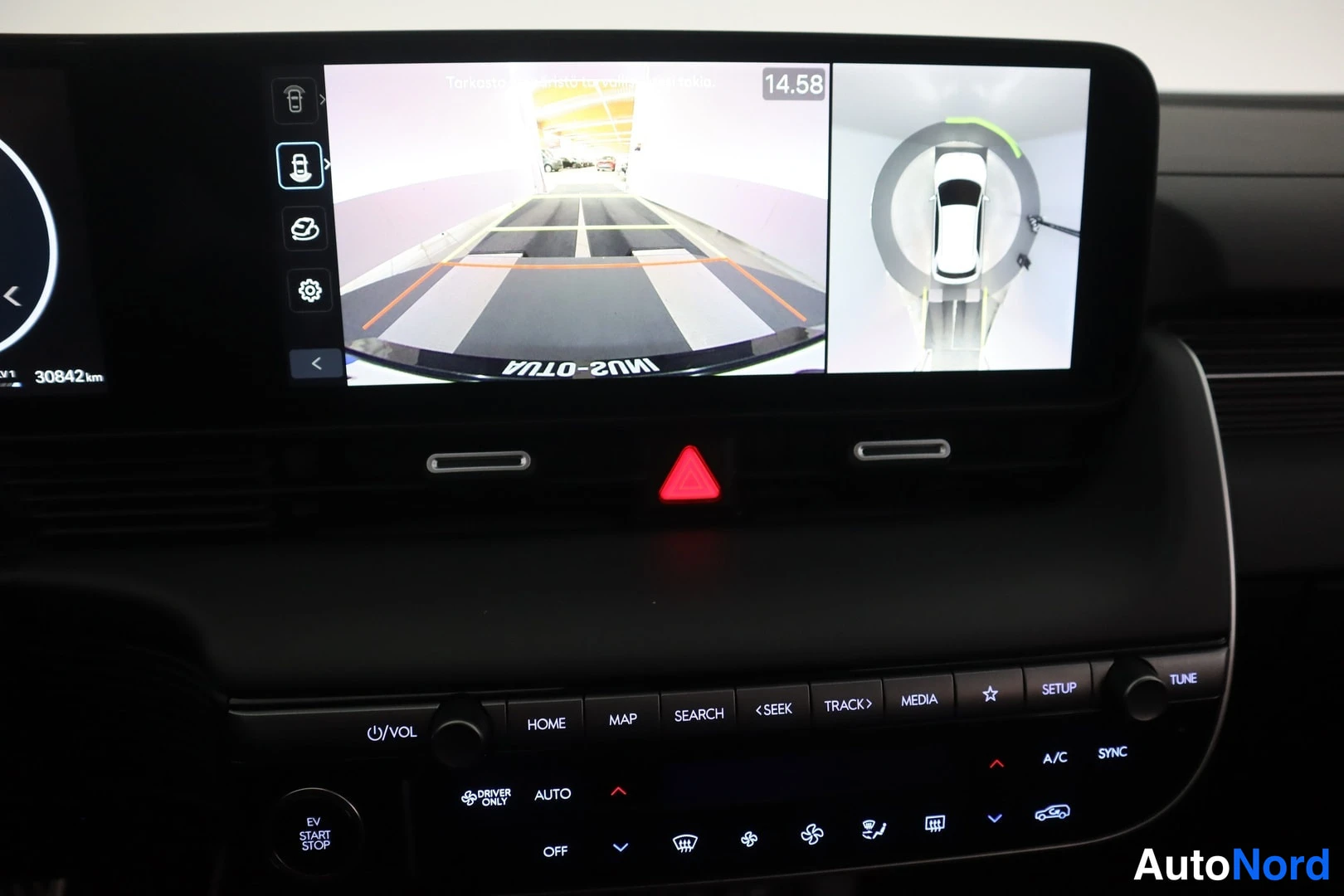 Muu: Kojelaudan näyttö, jonka vasemmassa osassa on peruutuskamera ja oikeassa ympärianturikameran 360-näkymä autosta ylhäältä katsottuna.