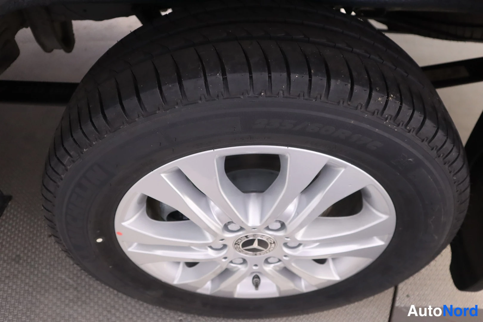 Muu: Lähikuva auton renkaasta ja hopeisesta Mercedes-vanteesta; renkaan sivuseinässä lukee '255/60R17C'.