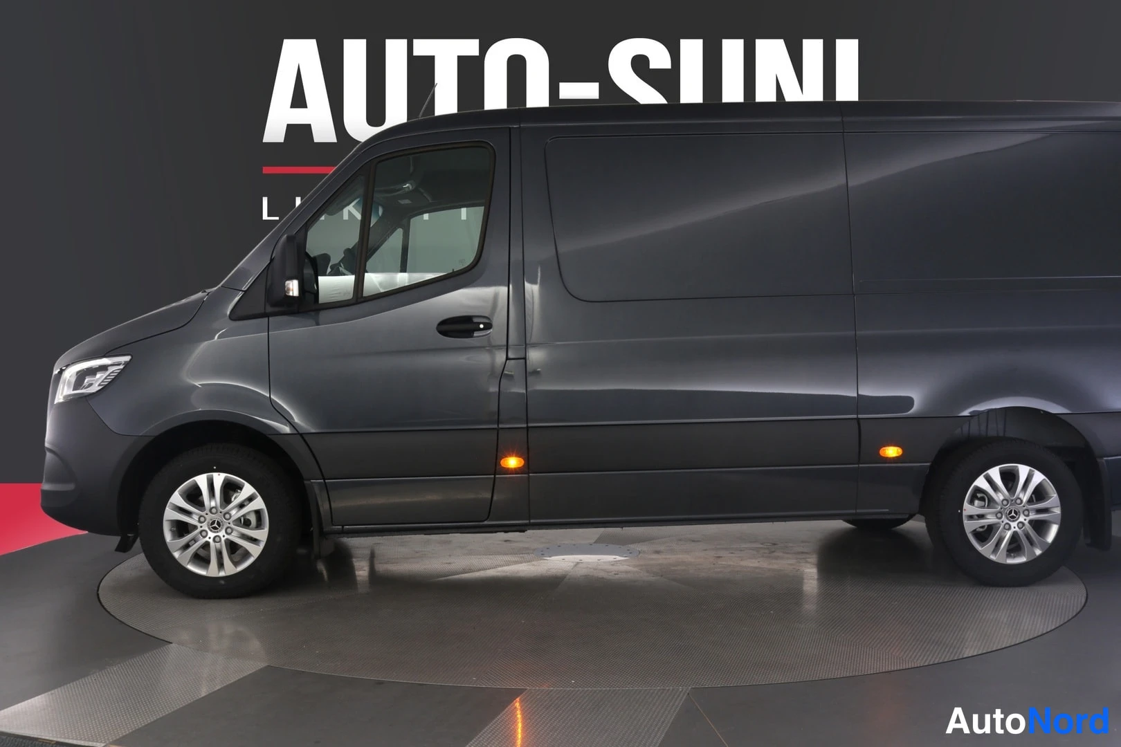 Etuviisto, nokka vasemmalle: Tummanharmaa Mercedes-Benz Sprinter -pakettiauto etuviistosta vasemmalle, studiovalaistus
