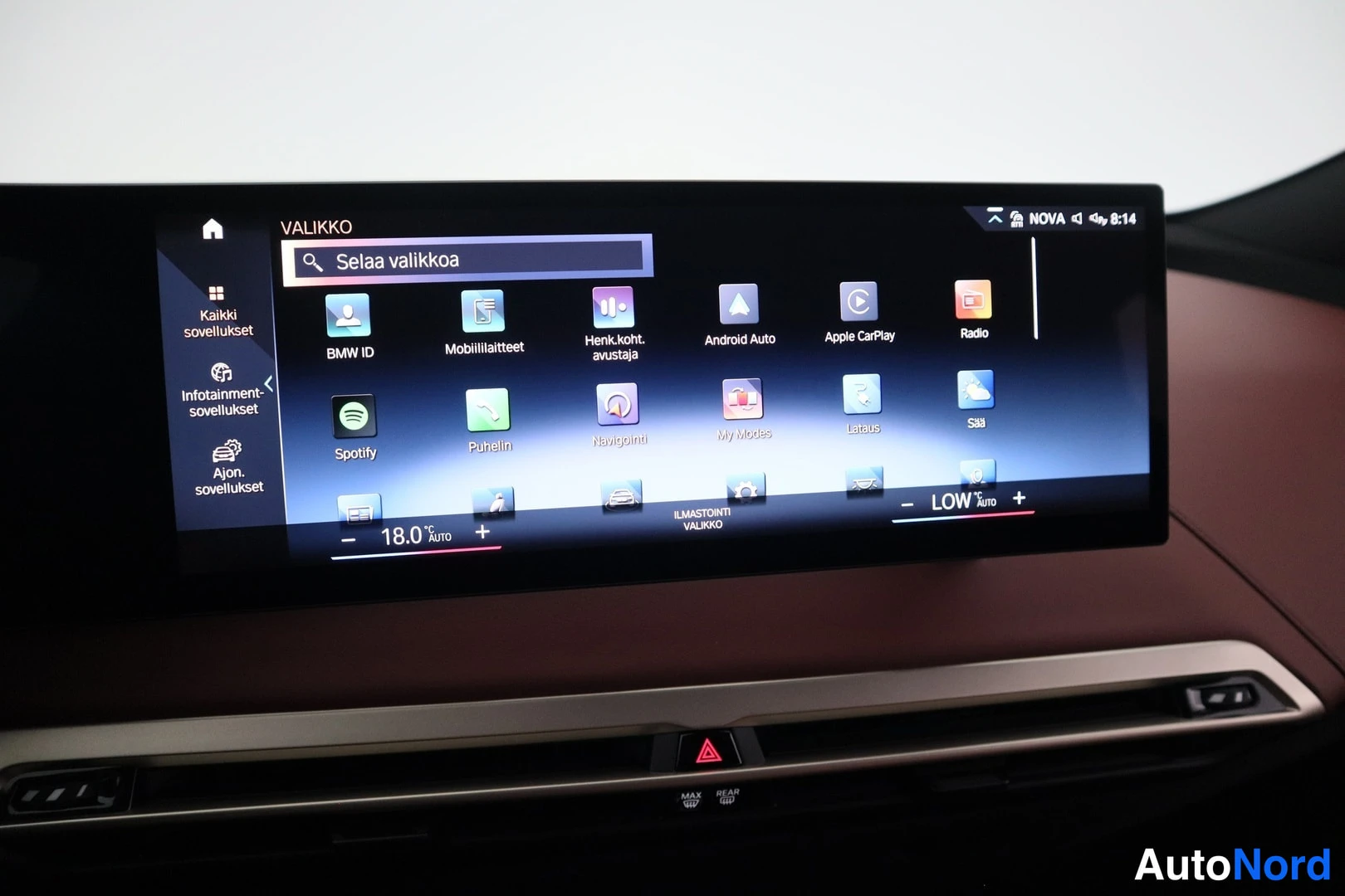 Muu: Auton infotainment-näyttö valikossa, jossa sovelluskuvakkeita kuten Android Auto, Apple CarPlay, Radio ja Spotify; alapuolella punaruskea kojelauta.