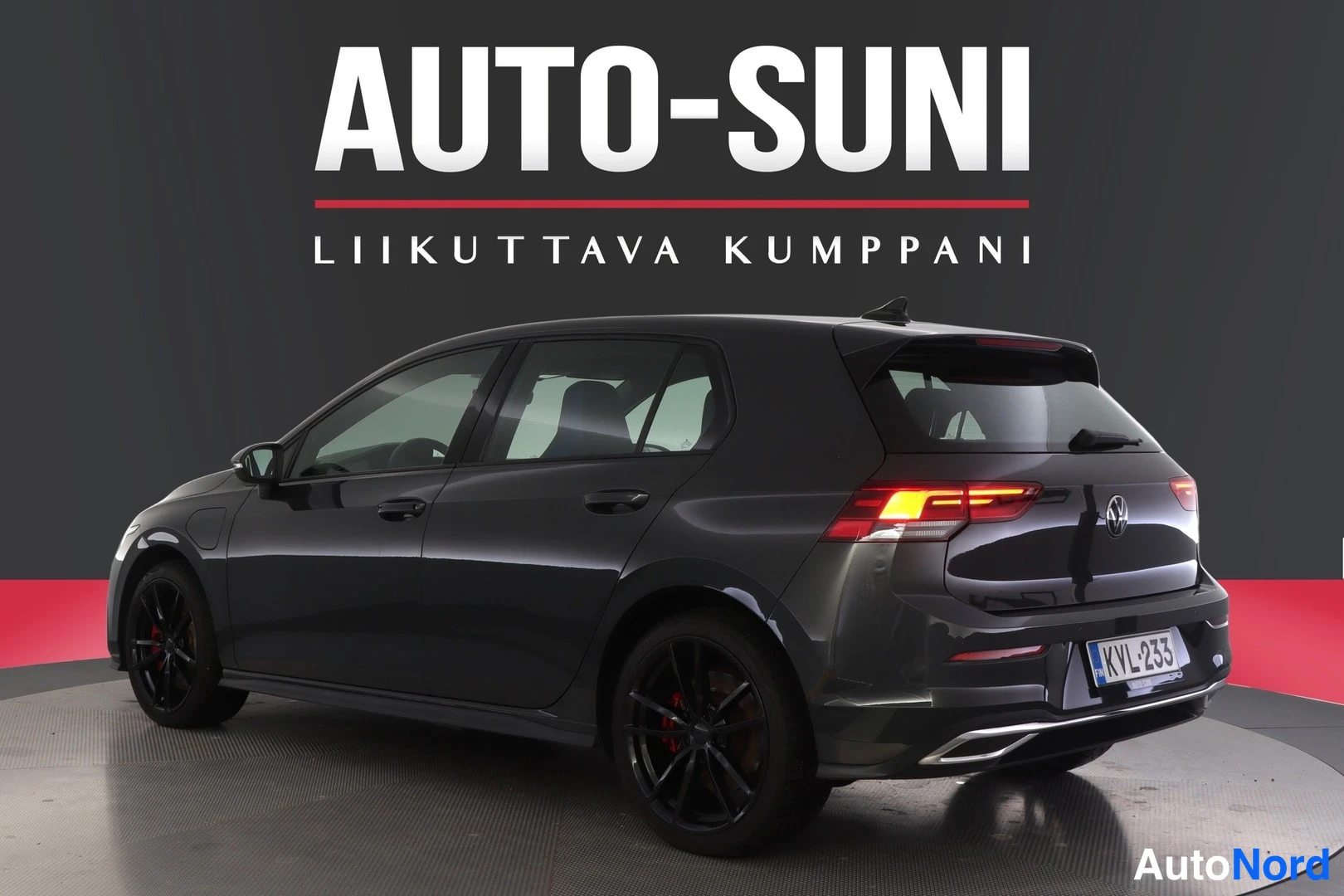 Takaviisto: Auton takakulma oikealta: tumma viistoperä, sytytetyt takavalot ja rekisteritunnus.