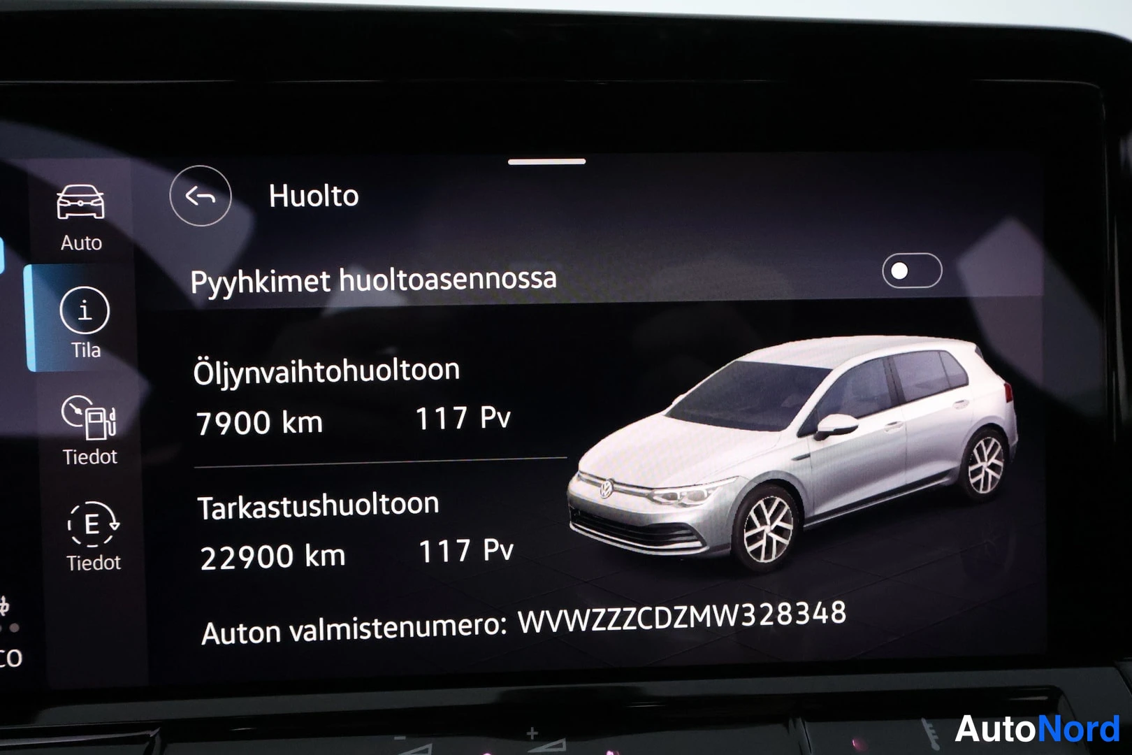 Yksityiskohta: Auton infotainment-näyttö Huolto-näkymä, jossa huoltovälit 7900 km ja 22900 km sekä valmistenumero