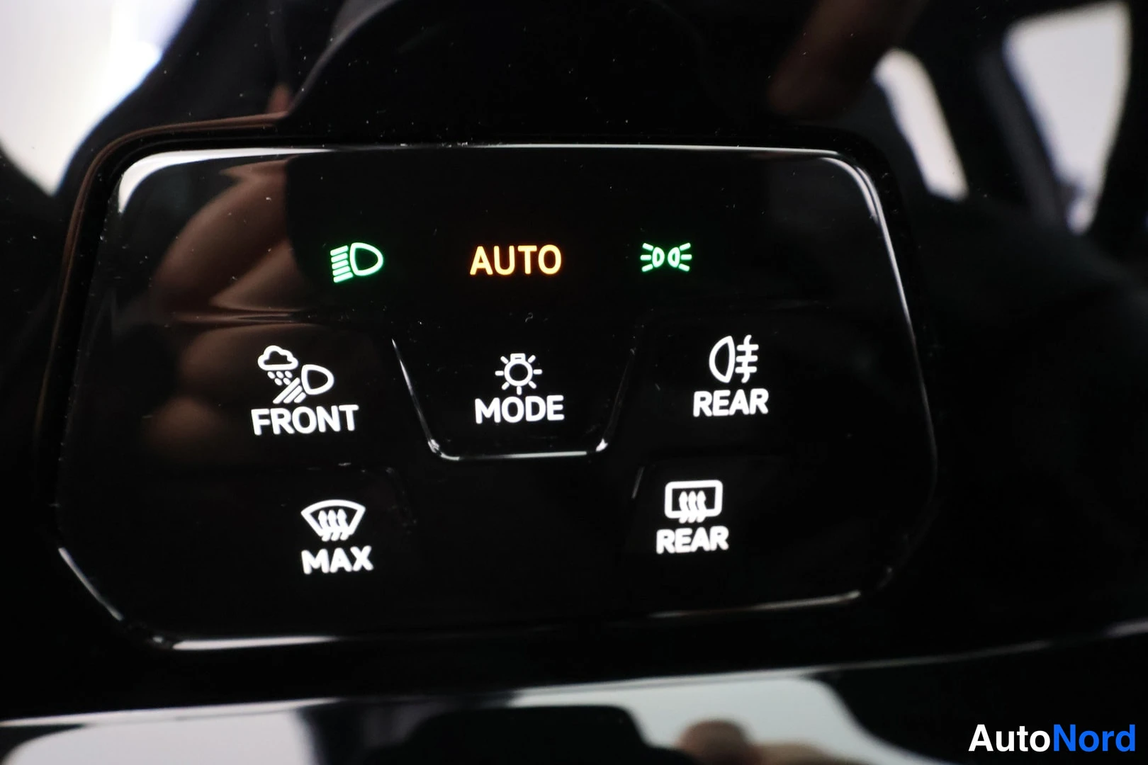 Yksityiskohta: Sisätilan kuva: kiiltävä musta painikepaneeli, jossa valaistut AUTO-, FRONT-, MODE-, REAR-, MAX- ja REAR-näppäimet ja merkkivalot.