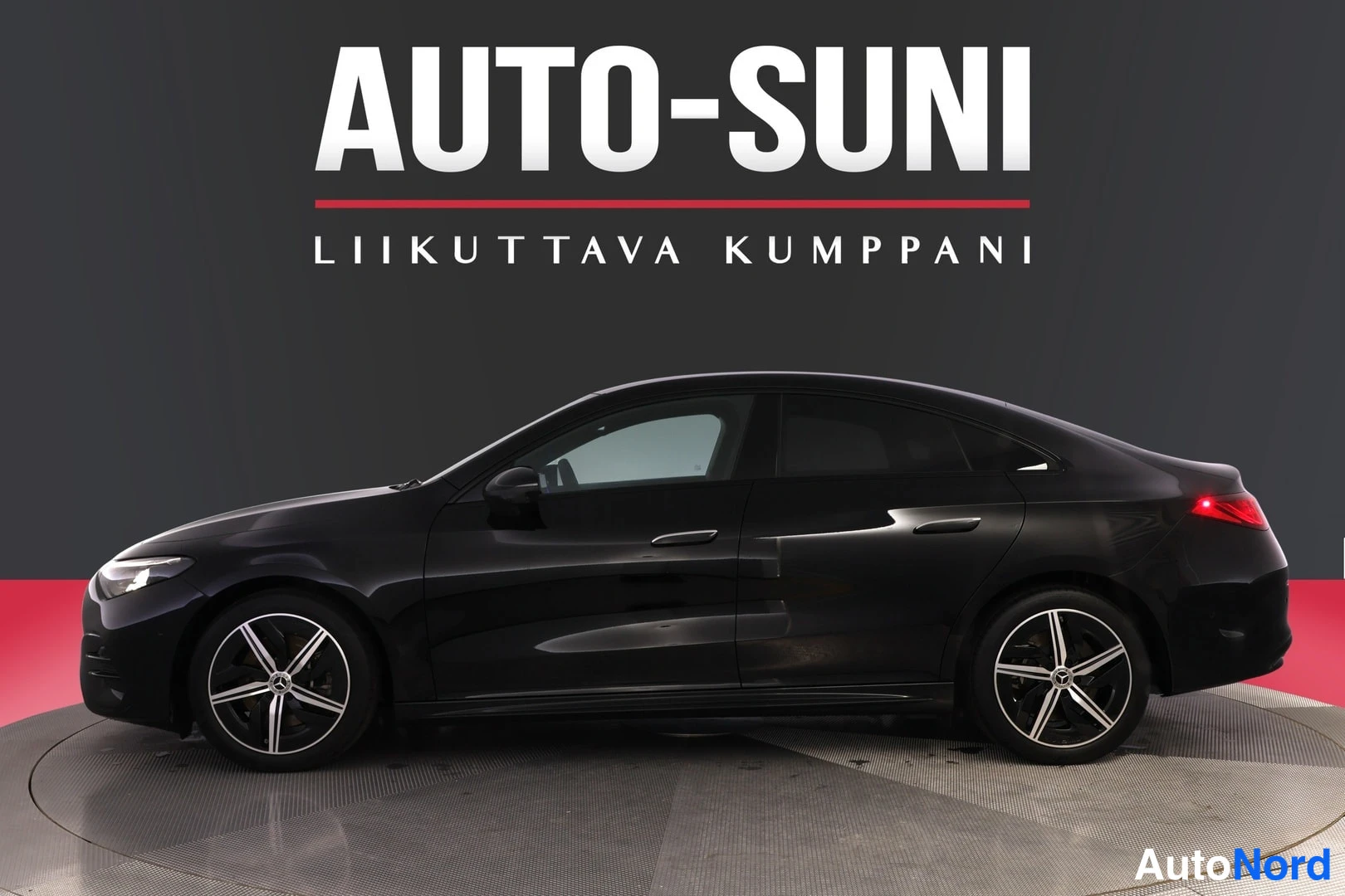 Sivulta: Musta Mercedes-Benz CLA -tyylinen sedan sivusta etuosa vasemmalle, AMG Line -tyyliset viisipuolaiset kevytmetallivanteet.