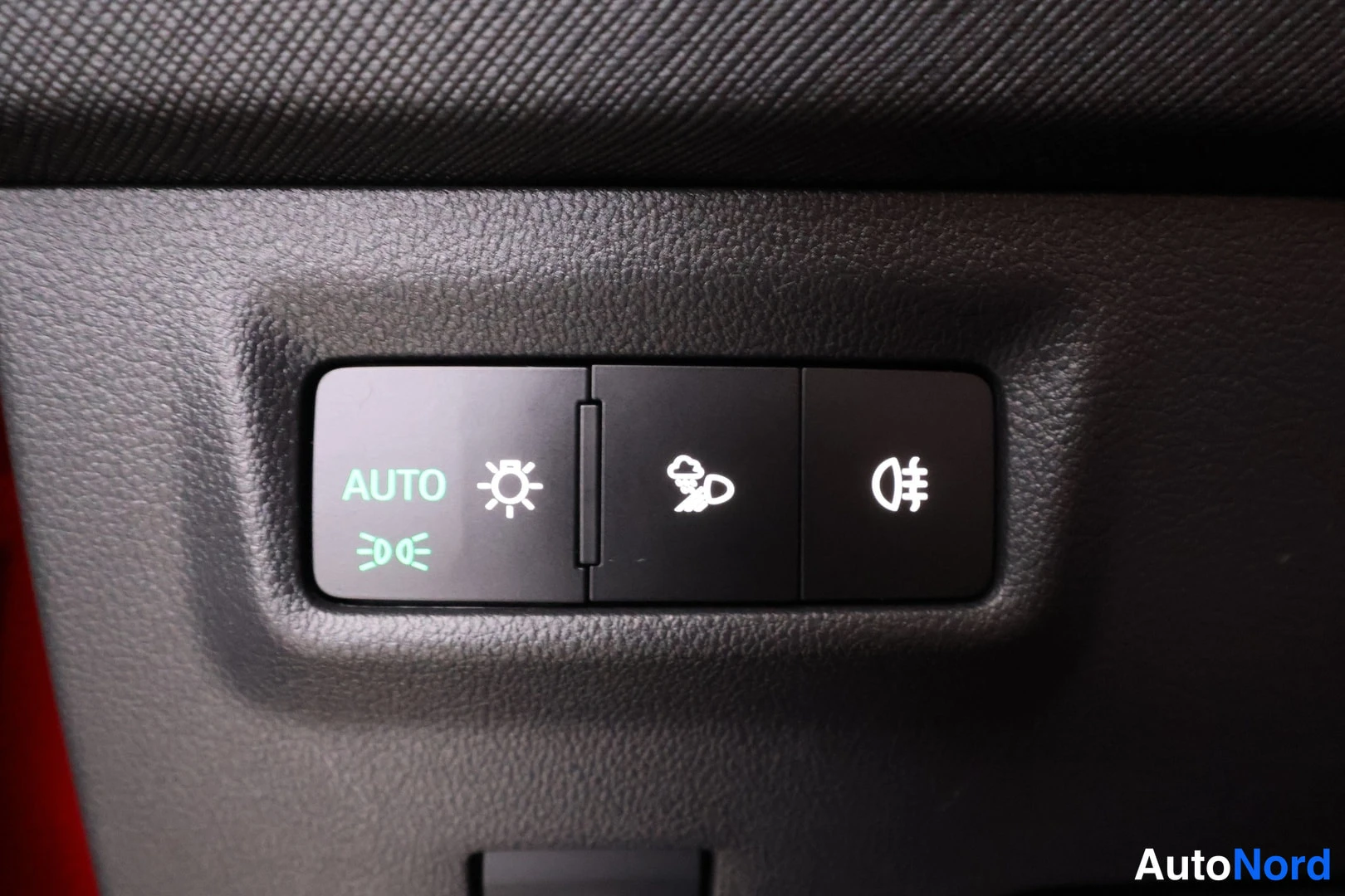 Yksityiskohta: Valojen hallintakytkin kojelaudassa, jossa AUTO-merkintä ja valaisimensymbolit.
