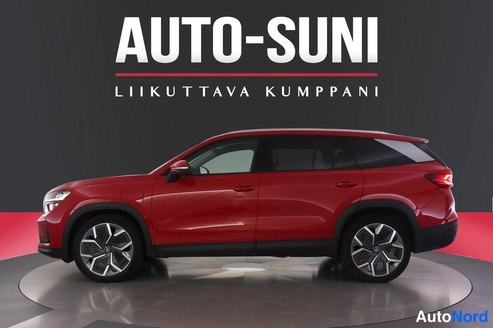 Sivulta: Punainen SUV sivulta kuvattuna näyttämöllä, AUTO-SUNI-logo taustalla.