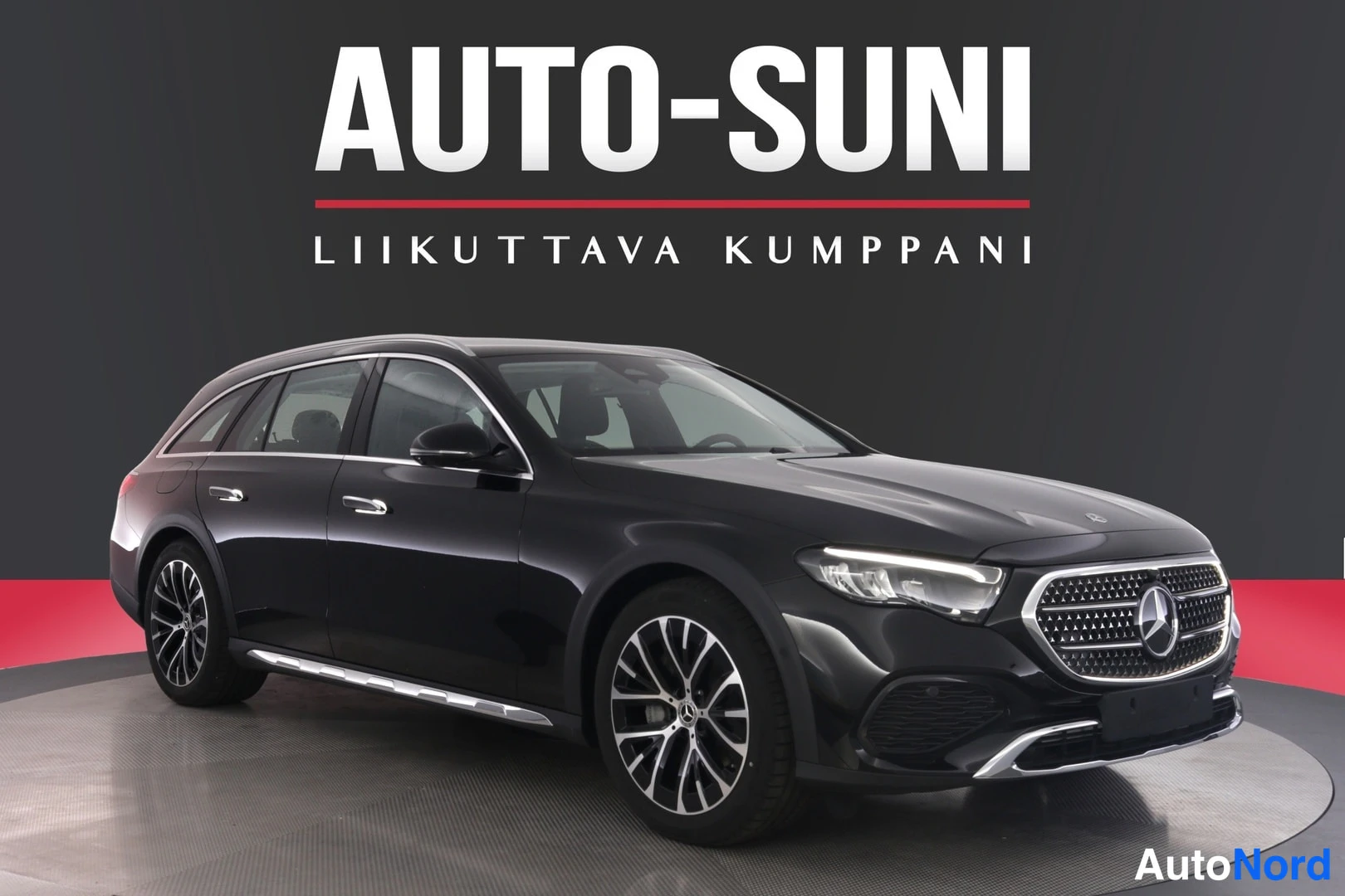 Etuviisto, nokka oikealle: Musta Mercedes-Benz farmariauto etuviistossa oikealta, metallivanteet ja kattokaiteet näkyvissä.