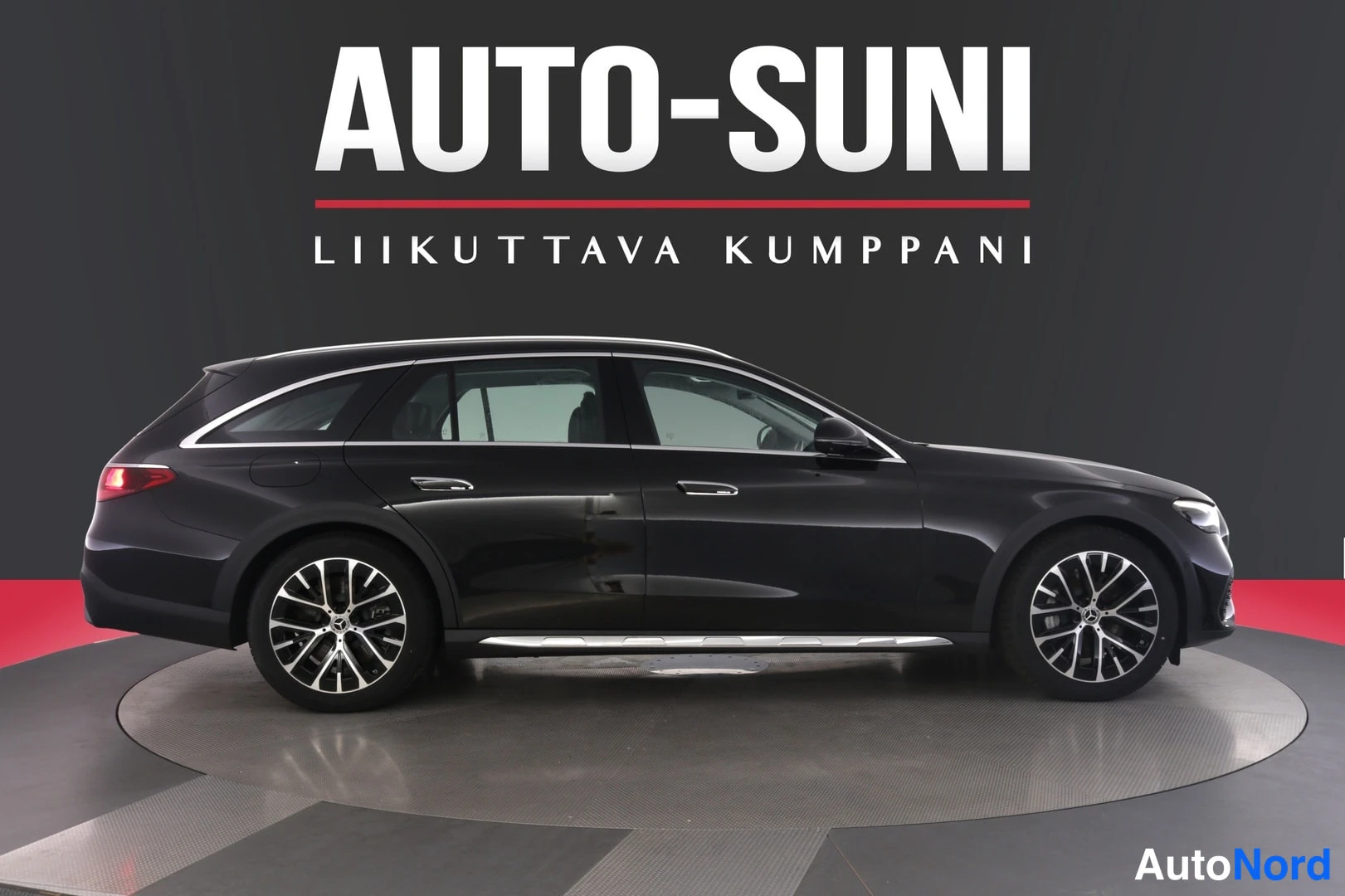 Sivulta: Mustan Mercedes-Benz farmariauton sivuprofiili studiotautustelussa, kattokaiteet ja metallivanteet näkyvissä.