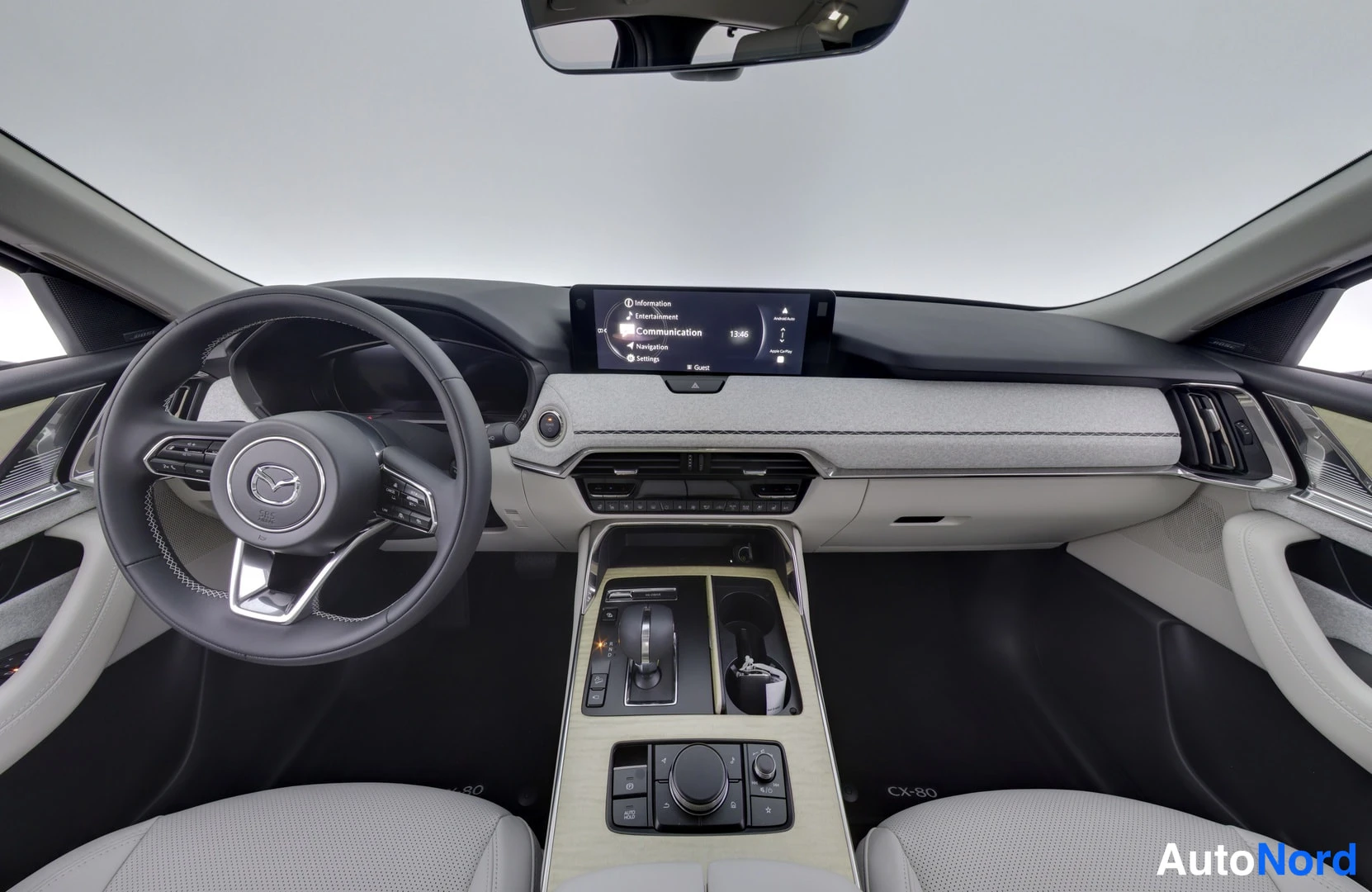 Ohjaamo: Interior cabin view showing steering wheel, dashboard with center screen, instrument cluster, gear selector and front seats.